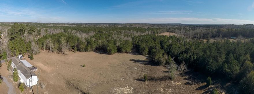 This home is situated on+/- 20 acres and is just a short 35 minutes to the beaches of the Emerald Coast and close to I-10. You won't find long range views over the hills this close to the beach. It is truly a one of a kind-must see. There is great pride of ownership in this 3 bedroom 2 bath home. The current owner performed a multitude of upgrades to the home and cleared 4 acres of land. This peaceful and private retreat is surrounded by beautiful countryside and is full of rustic charm. The kitchen features hardwood siding, new cabinets & sink and designer lighting. It is open to the dining area and flows effortlessly into the living room. The spacious living room is bright and full of natural light. Cozy up next to the Morsoe wood burning fireplace or step out onto your back porch and gaze at the stars.  Enjoy sweeping views of your land from your covered porch or open deck.  Retreat to your master bedroom where the owner added a picture window for picturesque views to the rolling hills.  One of the two guest bedrooms has an en suite bathroom featuring a new vanity, stand up shower with new tile and a closet.   The other guest bedroom has new carpeting and has a fun bunk bed perfect for kids.  The owner installed a camera and security system and the entry of the property is fenced.  There is so much you can do with your acreage.  Explore, camp, hunt or tend a garden.  The possibilities are endless.  We invite you to view this relaxing getaway today.