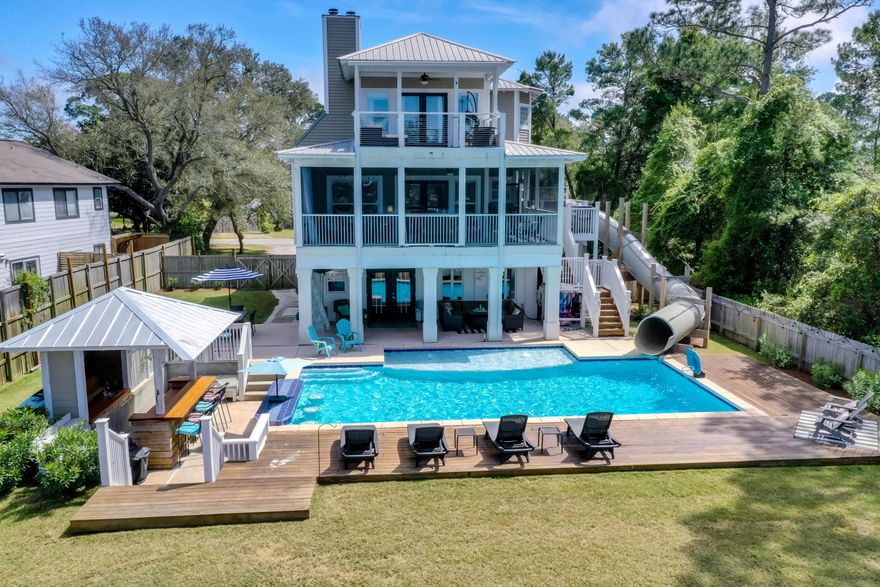 Beautiful Buck Bayou 3-story paradise with a 2-story water slide! Your private family fun resort. Five minutes to beautiful white sand beaches, shopping and restaurants. The home has a private suite on lower level, with full kitchen, living room, master bedroom, private bathroom, washer and dryer and pool table. The upper level of home on main level has another full kitchen, large living room, dining room, 2 guest bedrooms with large bathroom to share, laundry room, huge screened in back porch and front porch/balcony off of two guest bedrooms. The third level of home has Master Suite with private bathroom, jetted tub, walk in shower, and huge balcony for beautiful sunset views, having coffee or just lounging.