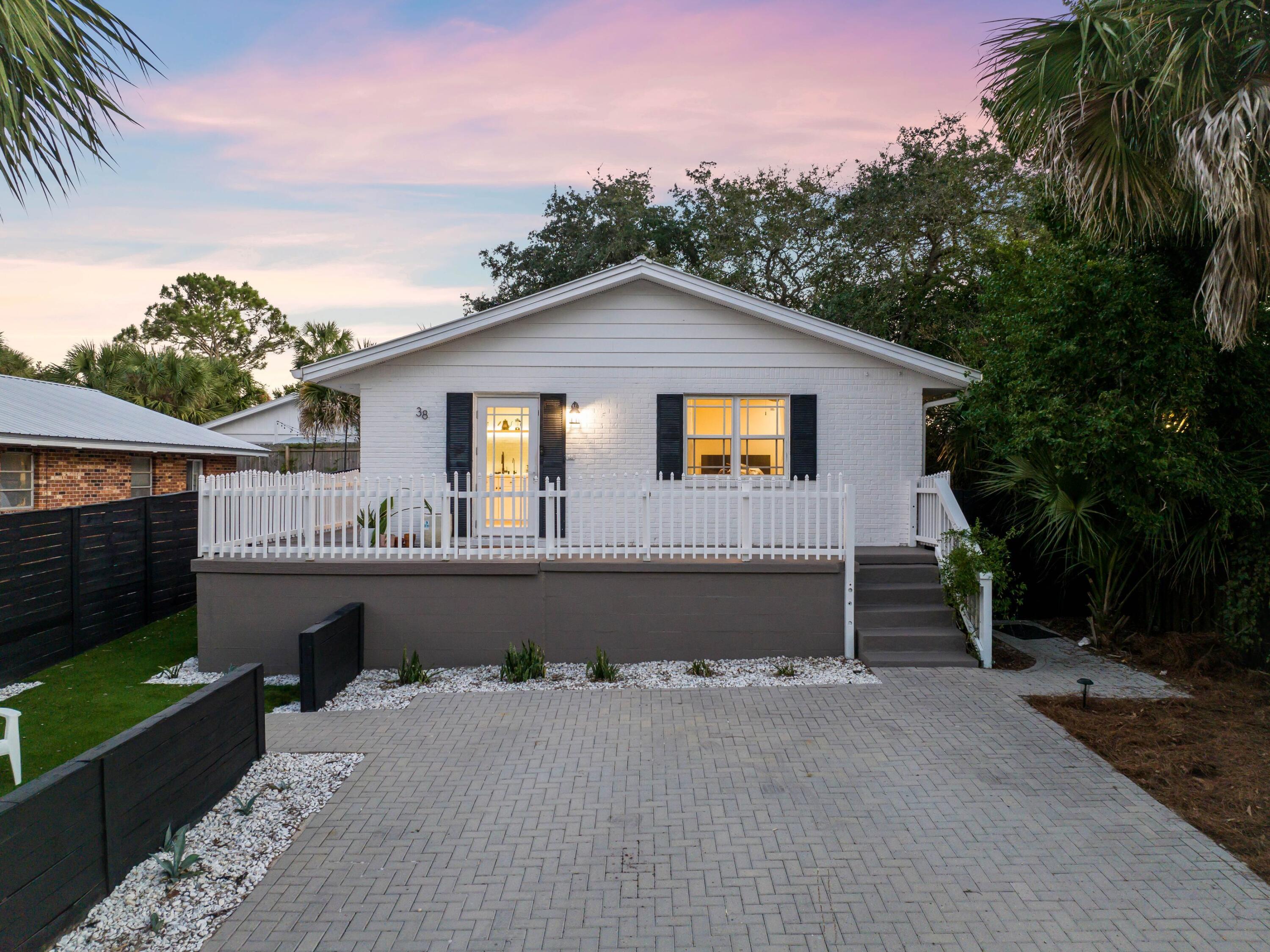 Check out this adorable beach cottage, situated directly off Scenic Highway 30A in Blue Mountain Beach. Fronted by a generous brick paved parking pad, this elevated single-story cottage has been tastefully remodeled and updated. It now boasts three bedrooms and two full baths, a rare bonus. It also has a newer roof and a replacement HVAC system. Wood-look flooring graces the entire cottage, along with narrow shiplap on the ceilings. After a busy day, return home and relax in the cozy sitting room, which showcases a feature wood ceiling and a neat chair rail. The remodeled open kitchen is bright and fresh with floating shelves and uplighting,. It has ample storage in floor-to-ceiling cabinetry and a gleaming glass tile backsplash behind the twin sinks and ceramic stovetop. This vacation getaway has a private fenced yard with a deck for dining and cookouts. Elsewhere, areas of grass and feature plantings add to the vacation vibe. Best of all, this charming beach house is just half a mile from the beach and has the added benefit of no HOA.