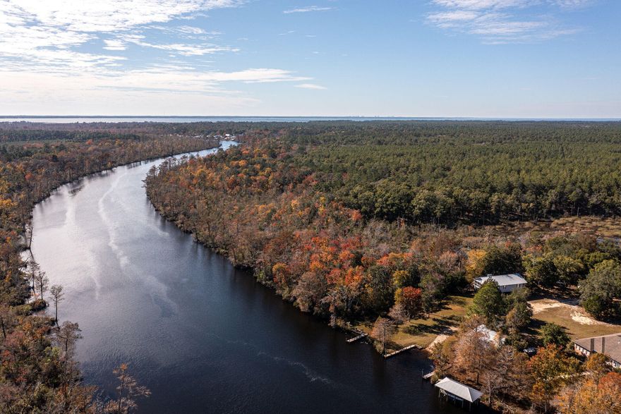 Discover nature's beauty on this peaceful .95 acre waterfront lot in Happy Hollow, featuring 83 feet of waterfront on Black Creek. Enjoy a serene, country-like setting with city conveniences just minutes away.  The lot is steps from a semi-private neighborhood boat ramp offering access to Black Creek, Choctawhatchee Bay, and the Gulf of Mexico.  The property includes a scenic view of the creek and a ''meander,'' or beaver pond! There is both city and well water available.  A large storage/well building with a paved picnic/work area is also on-site.  No active HOA or dues.  House plans are available.  Buyer to verify all dimensions and information important to them. Come build your waterfront dream home at 2 Creekview Ave!