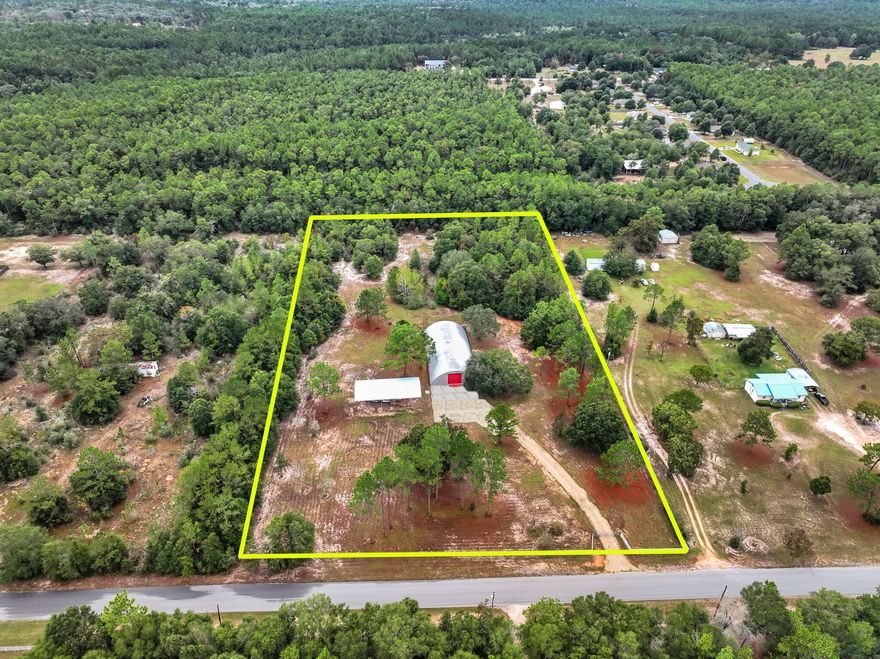 Located just outside the thriving Crestview corridor, this exceptional 4.47 acre property offers a rare blend of commercial flexibility and expansive outdoor space. Upon entering through newly installed electronic gates, you'll immediately appreciate the scale of what awaits: a 5,000 square foot Quonset hut set atop a 15 inch concrete slab, complete with a loading dock, full utility access, and a rooftop sprinkler system designed to moderate interior temperatures. Alongside the main structure sits a new pole barn sized for a 45 foot RV, and the site is further enhanced by two municipal water meters, a deep water well, two like new septic systems, and three full RV hookups including 30 AMP and 50 AMP service.