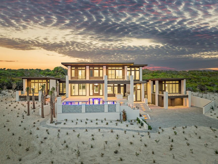 Coastal enchantment unites with progressive modern luxury at this bespoke new construction offering in the untampered community of Four Mile Village. Surrounded by the protected Coffeen Nature Preserve to the north and the Gulf of Mexico to the south, the serene neighborhood provides an idyllic locale for this prominent showcase home, situated on an elevated one-plus-acre parcel, one row off the gulf. Designed to be equally whimsical and bold, the progressive design bridged elements of mid-century design principles and married them with features designed to enhance contemporary beach living.