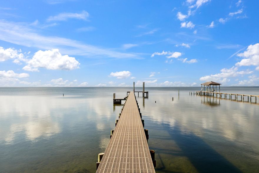 Opportunities like this don't come along often. Nestled on 0.82 acres with 102 feet of East Bay waterfront, this thoughtfully renovated 1960 home offers the perfect balance of character, comfort, and coastal charm. Located at 4536 Hickory Shores Blvd in Gulf Breeze, the property welcomes you with a long gravel driveway shaded by mature oaks and beautifully landscaped with native herbs like rosemary and sage. The driveway leads to a split two-car garage, a paver motor court, and a covered front porch that hints at the charm waiting inside.The entry opens directly into a beautifully renovated kitchen featuring white quartz countertops, shaker-style cabinetry, and stainless steel appliances. A prep sink near the window adds functionality, while a rich dark brown island with a farmhouse sink provides contrast and warmth. The space flows seamlessly into the living room, where oversized windows and a sliding glass door frame breathtaking views of East Bay. The living area includes custom built-in shelving flanking a gas fireplace and a ceiling lined with historic cedar wood salvaged from the 1930s Pensacola Library, adding a timeless and meaningful design element.

The original 1960 second story, accessed just off the living room, is full of charm, wrapped in wood from that same Pensacola Library. It includes two bedrooms with water views, one of which features a cozy windowed nook. The upstairs bathroom is preserved in its original condition and offers a perfect opportunity for customization.

Back on the main level, a versatile flex space includes a Murphy bed for guests and a hidden cubby concealed behind a bookcase, ideal for play or quiet retreat. A large utility room connects to the garage and offers ample space for laundry and appliances. Nearby, a shiplap-lined full bathroom and a walk-in pantry continue the home's blend of function and style.

The primary bedroom feels like a private retreat, designed with comfort and calm in mind. French doors open to the expansive back deck and bring in natural light filtered through the oaks. The ensuite bathroom features vintage-inspired tilework, an oversized walk-in shower with a rain shower head and wall-mounted fixture, and a thoughtfully designed layout that's both spacious and inviting. The walk-in closet includes two windows, offering not only ample storage but also a pleasant view and added light.

Step outside to a backyard that feels like a secluded bayfront resort. A lush lawn rolls gently toward a circular paver patio with firepit, leading to a brand-new seawall that extends the usable lot by 30 feet. A composite Thruflow dock stretches out into East Bay, with a mid-way platform perfect for shallow-water lounging or launching smaller watercraft. While not equipped with electricity, the dock is plumbed for freshwater and is ready for your next adventure on the water.

This one-of-a-kind property blends historical elements, smart updates, and unmatched waterfront living all within minutes of Gulf Breeze conveniences.