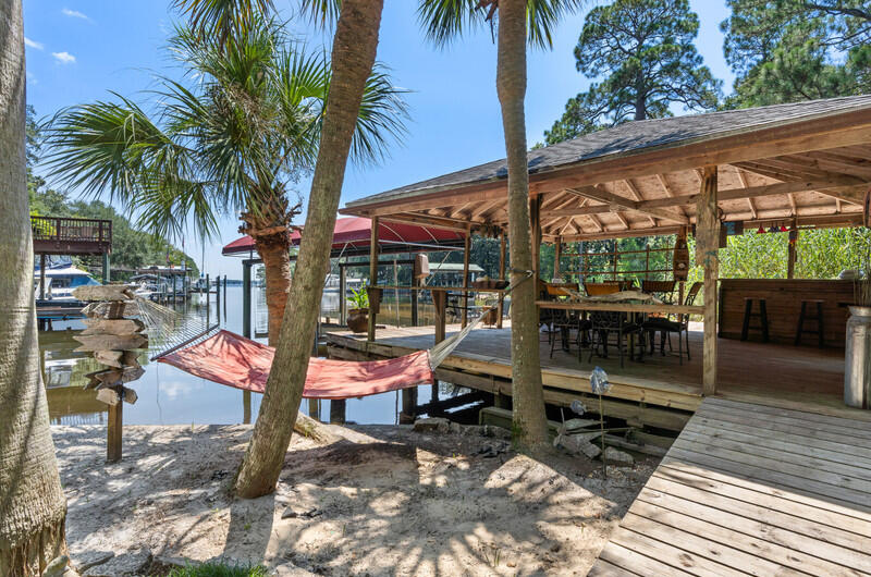 Own your own waterfront paradise! Located on the protected deep waters of Sarah Anne Bayou, this resort like retreat has everything you're looking for, from its deep water dock with boat lift, to a 20'x20' covered entertainment deck to a completely renovated home! The dock features 2 slips; one that previously held a large sailboat. Attached to the dock is a large covered deck overlooking a private sandy beach with a fire pit. Renovations include a spacious gourmet kitchen, an open living area, windows galore, including a wall of windows facing the bayou, hardwood floors, tongue & groove ceiling & even a wine room. A barbeque deck off the kitchen and a balcony off the master top it all off. New roof-2021, New HVAC-2019, Exterior paint and trim-2024. Second home? Furniture negotiable.
