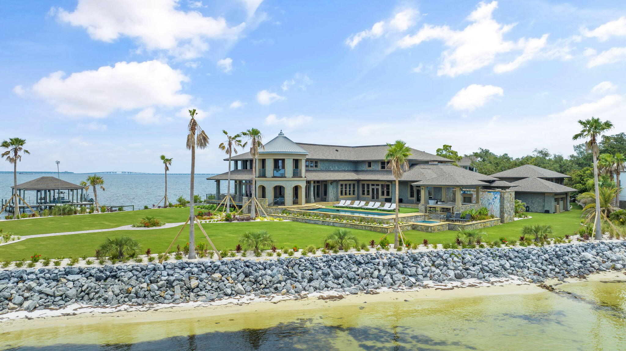 Enjoy the luxury of over 1,000 ft of waterfront on this Gulf Breeze property! Located in the highly sought after gated community of Peakes Point, this lavish and private 10,500 square foot home offers the best there is to offer both indoors and out. From the custom-designed bronze fixtures, to the sycamore and pear wood walls, the interior wow-factor is high! Modern amenities such as the fire suppression system, golf simulator/track room, generator, Control 4 Home Automation System, and hurricane rated impact doors and windows ensure comfort and security. Step outside to enjoy the beautiful views of both Pensacola Bay and Santa Rosa Sound from the yard equipped with an underground mosquito mister, upgraded landscaping, heated pool, hot tub, putting green, 2 jet ski lifts, 2 boat lifts,