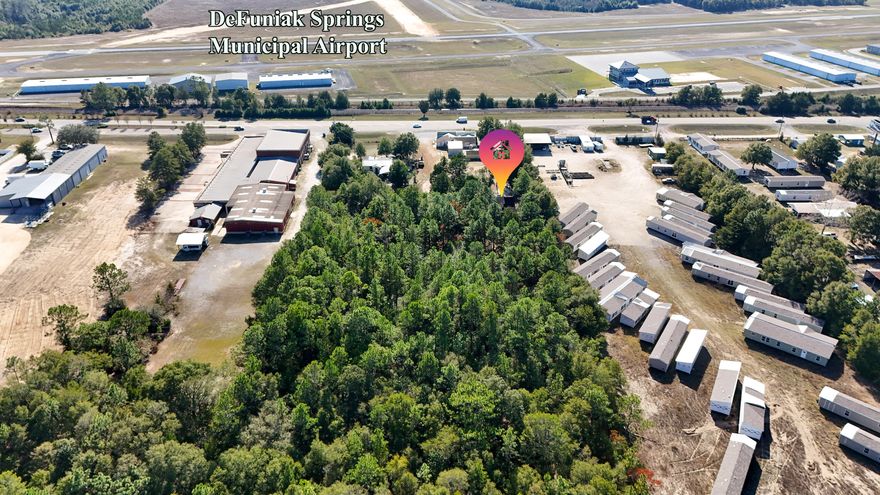 Commercial opportunity directly across from the DeFuniak Springs Municipal Airport. This 1.59 acre site includes a 1,650 square foot two story home with three bedrooms and three full baths. You can live on site, house key staff, or keep it purely as an operations hub. The structure is well maintained and functional, with room to update. The roof will need replacement and can be addressed in negotiations. The location places you in the path of airport related traffic and positions you well for uses like aircraft maintenance support, hangar-adjacent services, pilot lodging, aviation training offices, crew transport, rental car staging, drone services, or storage and logistics tied to air operations. The property backs up to woods and feels private while offering quick access to the airport.