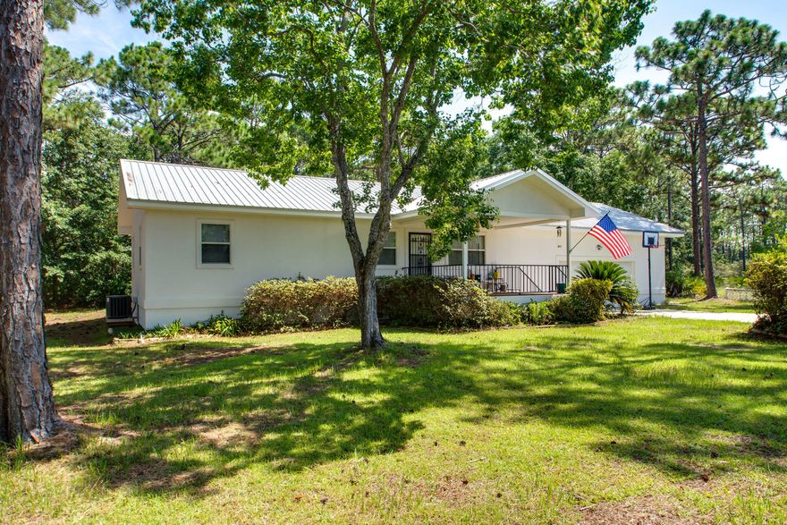 No HOA. Adorable Florida cottage on .5+ acre lot, convenient to shopping, dining, beach and all amenities the area has to offer. The open floorplan is just right for modern living and opens to the large rear deck. The kitchen features all appliances, plenty of cabinet space and a picture window with views of the beautifully wooded back yard. The master bathroom suite offers a dressing area and a private shower area. The guest bedroom has plenty of natural light and access to the additional full bathroom from the hallway. Luxury vinyl flooring and tile flow throughout. The two car garage, with high ceilings is ideal for storage space. Both the front and back patio decks are equally spacious, with no neighbors to the back.. Extended driveway for guests and an additional parking pad. New HVAC