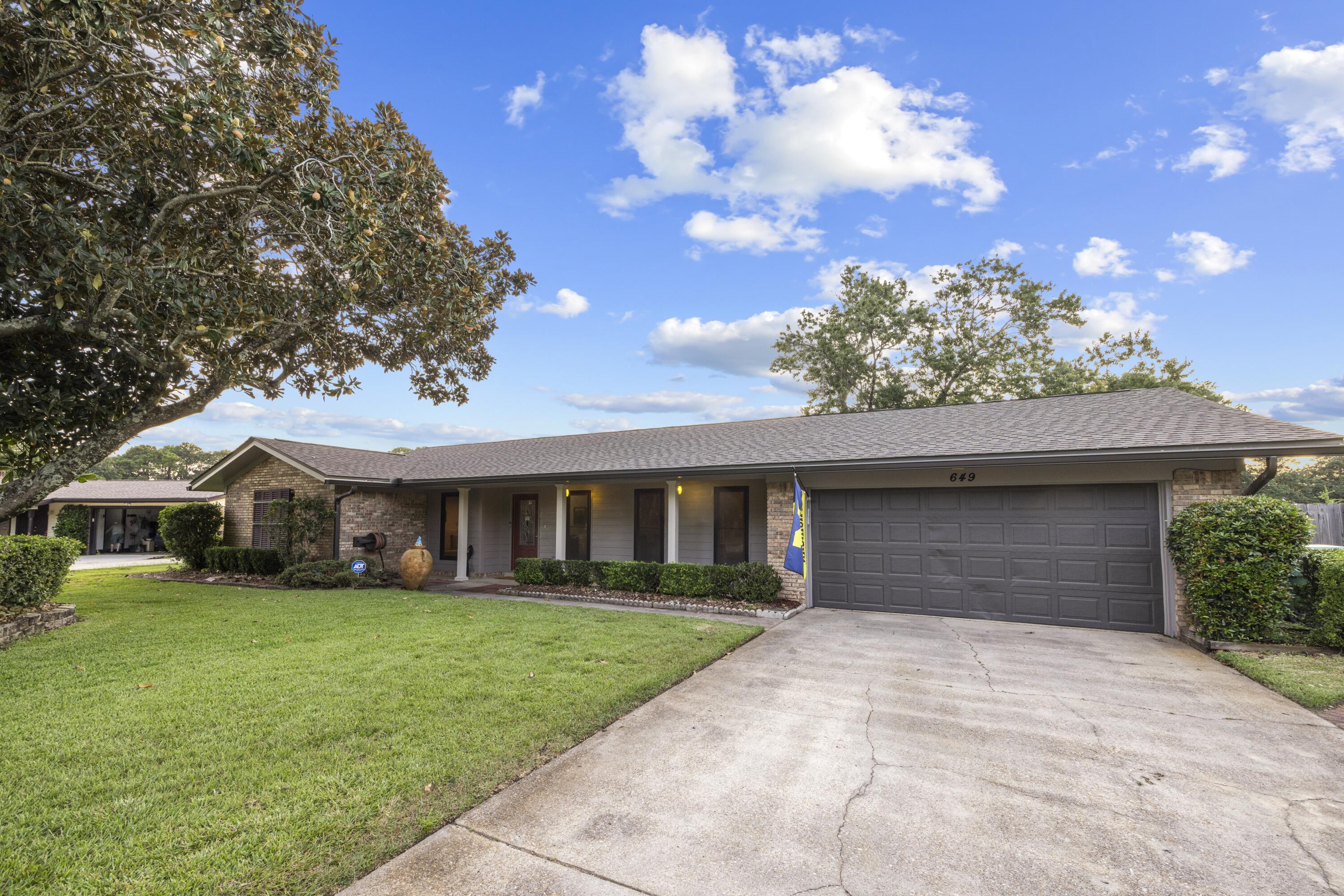 Welcome to 649 Overbrook Drive, a beautifully updated home nestled in the well-established Fort Walton Beach neighborhood of Overbrook with mature trees and sidewalks. Centrally located to both Hurlburt Field and Eglin AFB, this is an ideal location for Active Duty and DOD personnel. Fort Walton Beach is rich in activities and scenery such as public parks and recreation, emerald water beaches on Okaloosa Island and nightlife in downtown Ft. Walton Beach. With many shopping and dining options nearby, there's something for everyone. This 4-bedroom, 2-bathroom residence features a new roof (August 2024), HVAC system (2020), and water heater (2018) offering peace of mind and efficiency. Inside, you'll love the vinyl plank flooring throughout and the abundance of natural light pouring in through large vertical dining windows and multiple expansive living room windows. The open-concept layout seamlessly connects the living area to a thoughtfully designed kitchen boasting floor-to-ceiling honey oak cabinetry, including pantry space, granite countertops, a kitchen island with bar seating, stainless steel appliances, and a deep white enamel dual-basin sink. The primary suite is generously sized and features dual closets, while the en-suite bath is a standout with custom tile work, cabinetry, and a sleek glass tile shower. Step outside to enjoy the expansive, privacy-fenced backyard, complete with a covered lanai, extended paver patio, exterior storage room, and a sprinkler system with lawn pump. The covered front porch adds even more charm to this inviting property. Don't miss your opportunity to own this move-in ready gem!