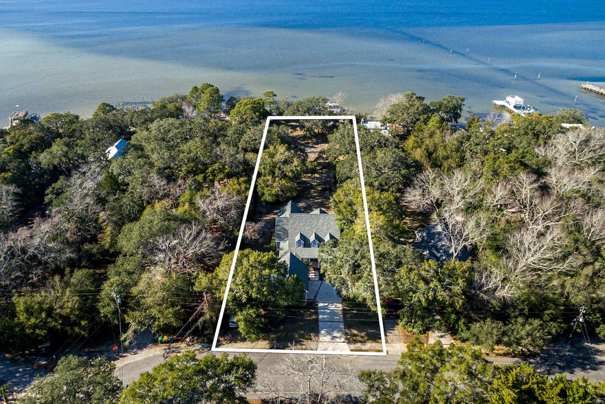 A cathedral of native oak trees drip with spanish moss on over an acre of welcome oasis, year round sunsets, and sparkling bay waters. Traditional southern architecture meets coastal chic in
this well-appointed four bedroom, four and a half bath bay-front home. This home invites relaxation beginning with the concrete and brick lined driveway and welcoming covered front porch,
through the large landscaped backyard, and ending past the waters edge. Destin's popular Crab Island and the sugar-white sand beaches of the gulf are mere minutes by boat through the East Pass. Two lots combine for 100' +/- of total bay
frontage and offer the opportunity to build a second dwelling on the eastern lot with 82' of frontage. A lofty two-story brick fireplace overlooks a wall of windows
and hearth serves as the focal point of the family room, complete with a wet bar for easy entertaining. At the heart of the home, the gourmet eat-in kitchen features a large island with plenty of cabinets, upgraded appliances, and a gas range. Stunning
Australian cypress flooring completes the warm tonal composition and could be expanded to all living areas. Custom-built bookshelves line an office wall while natural light pours in through
one of the many windows in this home. The master suite on the main level boasts a private patio and spacious attached master bathroom. Another full bath, dining room, and large laundry
room complete the main level. Three additional bedrooms, two bathrooms and a bonus room are found upstairs allowing for plenty of space and privacy for guests. Calhoun Avenue is a quiet neighborhood
conveniently located near Destin's Harbor front entertainment and dining complex.