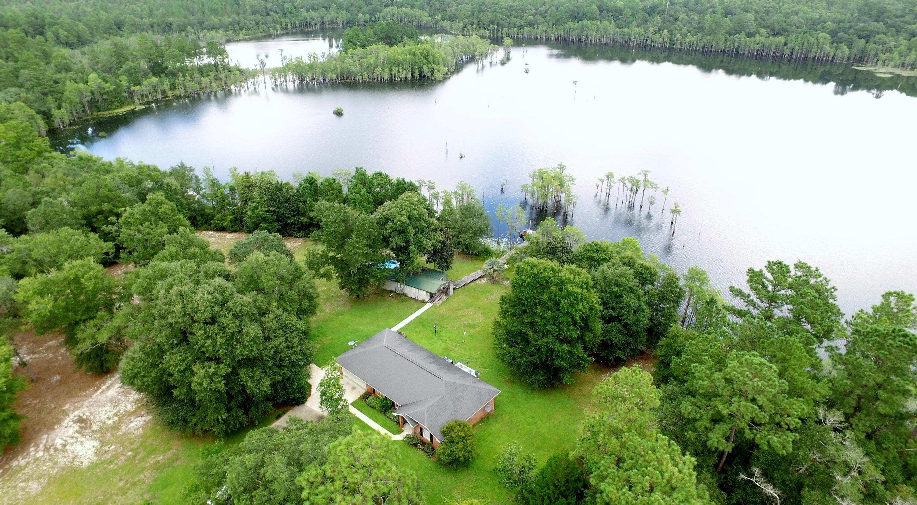 Dreamy Waterfront Oasis! This is an ideal second home located just a few minutes from the 18 hole Sunny Hills golf course. Additionally, there is a guest cottage with a pool on the property. Together, both homes comfortably sleep 8 people and can be sold furnished or unfurnished. The property features 240 ft of waterfront with a long fishing pier. There are currently only 3 homes on Gin Lake as the majority of the lake is greenbelt land owned by the subdivision. The beautiful main brick home was built in 2003. Wonderful features of this home include 18'' tile flooring, whirlpool tub, walk-in closet, great views of the lake, breakfast room, sidewalks, storage building, and water softening system. Sunny Hills has several lakes and a clubhouse. Both homes are on a water filtration and softening system. Home warranty being offered to the buyer at closing. Sunny Hills is located within 12 miles of the interstate, within 45 miles to the international airport and The World's Most Beautiful Beaches of Panama City Beach.