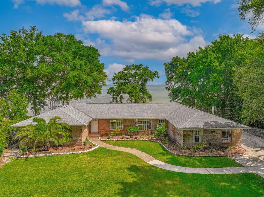 Situated along beautiful East Bay in Gulf Breeze, enjoy sweeping bay views throughout this traditional all brick ranch with a 5bed/5bath primary home plus an attached studio apartment with private bath. Enjoy the picturesque views from the comfort of your home or from the private dock with boat slip. A new 101ft seawall to be completed along with a new roof prior to closing. A step inside reveals bright and open spaces with a spacious living room with custom built-ins, a wall of windows, and French doors that lead to a large deck overlooking the bay. The kitchen offers a large breakfast bar, tiled countertops, ample cabinets, and stainless-steel appliances. Dual master bedrooms with bay views and ensuite bathrooms, along with three additional bedrooms (one with an ensuite), offer ample