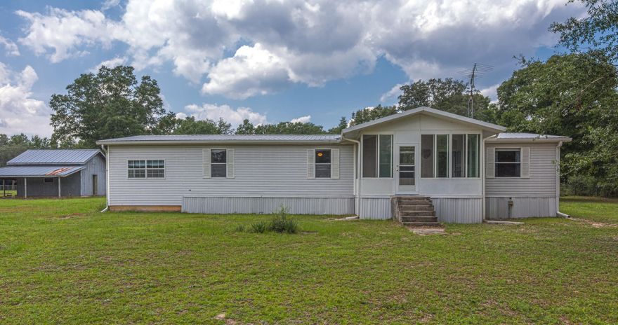 Neat and tidy manufactured home situated on approx 2 acres and CLOSE TO TOWN. The 3 bd/2 ba double wide manufactured home features an inviting front porch/Florida room (not heated and cooled) and spacious living room with wood-burning fireplace. Kitchen has lots of cabinetry, a breakfast room and formal dining room. Nice master suite; master bathroom has dual vanities, separate shower and garden tub. The home is a split bedroom design. A bonus/flex space measuring approx 11.5'x25' is to attached to one side of the home (not included in the heated and cooled sf). Workshop on property and fully fenced lot. Well water for indoor and outdoor water supply. PROPERTY TO BE SOLD IN 'AS IS' CONDITION! Buyer to verify all areas of importance.