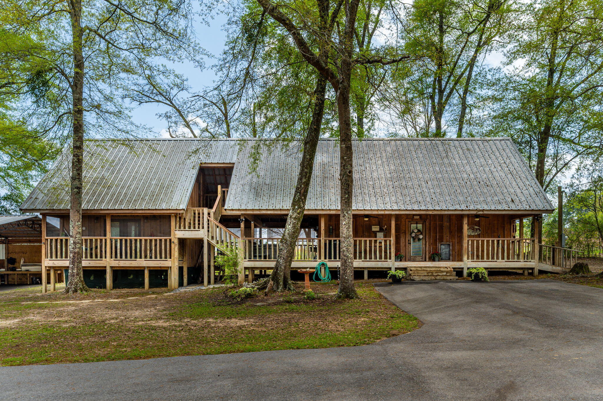 Welcome to Your Private Retreat - A Rare Gem That Truly Has It All  !!!Enter the property through a solar-charged decorative gate that sets the tone for this unique and well-appointed estate. The main cabin, built on sturdy pilings, showcases warm cypress walls and floors, spray-foamed insulation ceiling and batten walls which creates a cozy and inviting atmosphere. Stay comfortable year-round with the more than ample split unit for AC and heat. Thoughtful touches like under-stair storage and ample closet space ensure functionality matches beauty.Three spaciously private bedrooms each have their own bathroom. The master suite radiates elegance with its double-door entrance, coffered ceiling, and a timeless clawfoot tub--ideal for unwinding in style. A separate loft bedroom  ( con't ) with its own half bath adds privacy and versatility, perfect for guests, a home office, or a peaceful escape. The extra-large third bedroom is located upstairs with its own half bath.
Step outside to the 12x25 fiberwood-covered deck, built to last and designed for enjoymentwhether you're watching TV outdoors or soaking in the two-person hot tub under the stars. Additional outdoor amenities include a garden sink and shower with hot water, enhancing your connection to nature and convenience.
But the real showstopper is the 24x100 barn-dominium, built in 2017 with comfort and durability in mind. This impressive structure features 2 additional bedrooms and 2 baths, spray-foamed insulation, and soaring 16-foot ceilings. The open floor plan is perfect for entertaining and includes a gas stove, refrigerator, and two ice machinesone built-in under the counter and one free-standing. Whether you're envisioning a venue, guesthouse, or ultimate party barnthis space delivers.
Bring your RV! There's a 20x40 enclosed parking area designed just for it, plus a 24x50 carport with electric and water, complete with an attached 18x32 lean-to. An additional 12x50 covered area provides even more space for equipment storage or entertaining. And for the outdoor enthusiast, a private gun range adds a finishing touch that makes this property truly stand out. Don't forget the chicken coop! 
Whether you're seeking a multi-generational living solution, a place to host unforgettable gatherings, use as a Venue or a secluded personal retreatthis property checks every box and then some!
