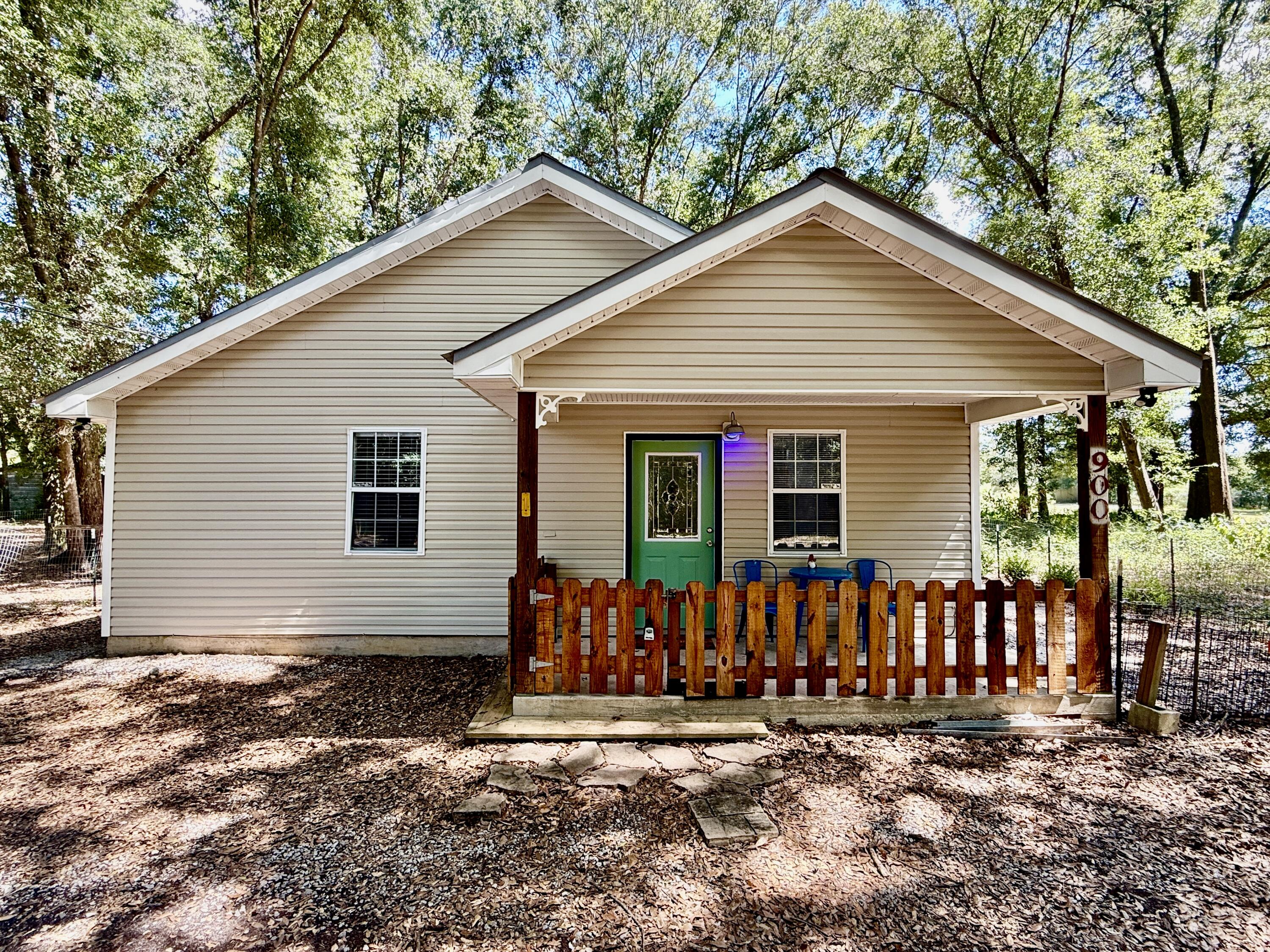 New photos are coming soon! 7.89 acres of privacy surround the cutest 720 sq ft, one bed and one bath, cottage. The bedroom has ample room for one king bed or two queen beds. There is a washer and dryer in the hallway. Central A/C and heat. All electric. New water heater installed in September 2021 and new AC in 2023. The refrigerator and stove are new. The interior has been freshly painted. Front porch, the side, and the back are fenced for pets. Floors are all tile and there is no grass outside to maintain. Kitchen has a hanging pot rack and windows have blinds. Property has one utility metal shed on concrete slab. Furniture is negotiable. Scenic walking trails are on the property,