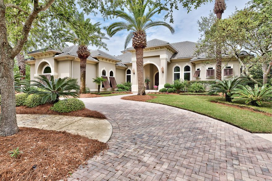 As seen after passing into a stately formal living room through opulent wrought iron entry doors, the elegant infinity edge pool of this Boswell-built Burnt Pine residence appears as one with the tranquil lake beyond it. Reflecting off its placid surface are the rolling greens of the 5th hole which can be seen from the pool, or any one of the seating arrangements beneath the screened lanai or gleaming wood ceiling of the sheltered outdoor room. With a fireplace, built-in TV cabinet and outdoor kitchen with kegerator, why spend time indoors? The only possible answer could be the great room. Its designer kitchen is appointed with two-tone raised panel cabinets featuring turned wood accents, honed granite slab counters, bar seating, and built-in table ideal for quick casual dining.