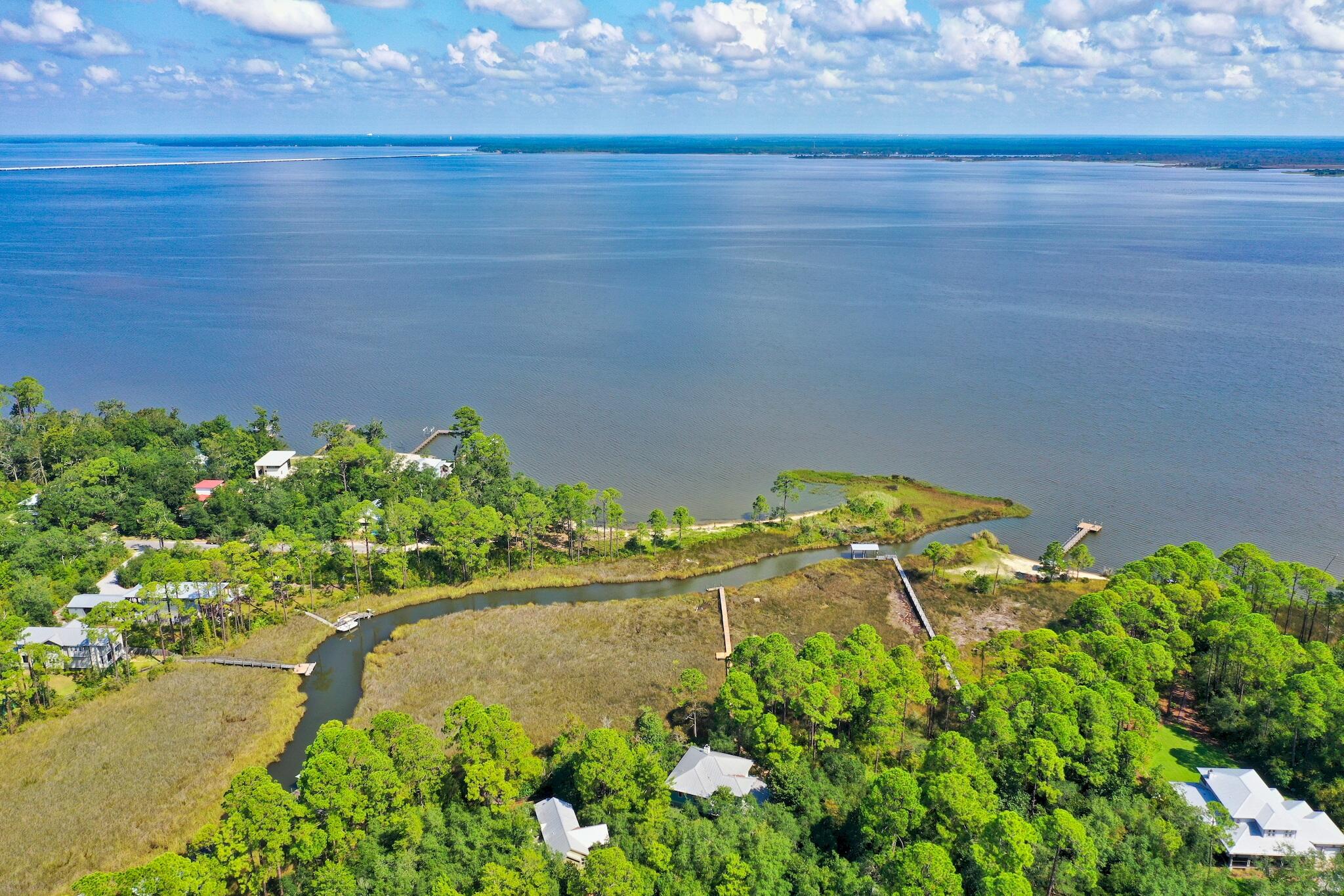 Welcome to Point Washington, waterfront living at its finest! Nestled amidst a lush tapestry of native vegetation, this meticulously crafted home boasts 179 feet of deep-water frontage, offering unparalleled vistas and direct access to the Choctawhatchee Bay. Enjoy breathtaking views of the grassland and bay from both levels of the interior space and three expansive screened porches spanning 700 square feet. Your private oasis is adorned with sprawling oaks, magnolias, long-leaf pines, cinnamon ferns, and palmettos, creating an idyllic setting that beckons coastal birdlife.A pier extends into the deep-water bayou, equipped to accommodate a boat lift, ensuring swift access to the bay.
