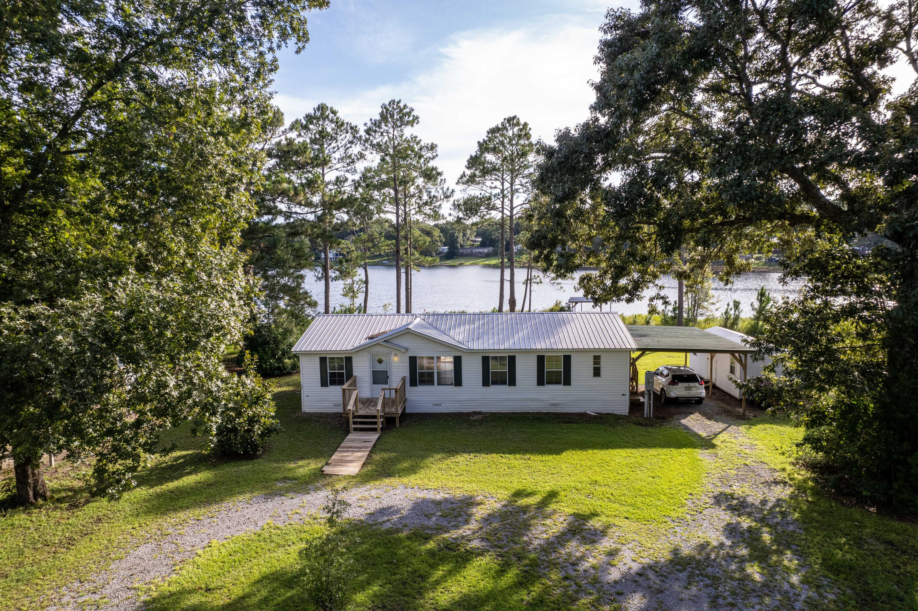 WATERFRONT HOME NOW AVAILABLE.. WITH COVERED BOAT DOCK/PIER.. STORAGE SHED WITH ELECTRIC.. AND RV HOOKUP!!! Who's ready to fish? This 3 BR/2 bath mobile home is on PARADISE ISLAND.. and is surrounded by Kings Lake; a 580 acre lake that connects to another popular fishing spot-- Holly Lake. Watch the holiday fireworks display from your covered back deck.. or gather around the firepit and roast marshmallows under the stars. This private lake is only accessible to property owners/guests, and there is a private boat launch as well. Fish from your backyard boat pier/dock.. or launch the boat and discover your own secret fishing hole. The bass are plentiful and so are the bream!There are 3 spacious bedrooms inside, as well as 2 bathrooms. The home has luxury vinyl flooring