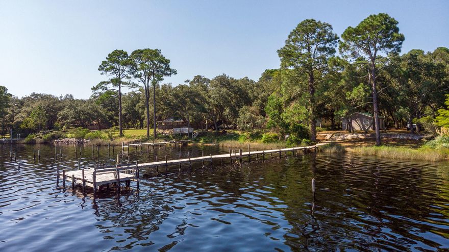 Come fall in love with this picturesque waterfront property on the bay. Serene panoramic views of the water will amaze. Property is perfect for building your dream house, your home away from home, or family fishing retreat. Features an adorable 480 sq ft cottage with 2 bedrooms and 1 bathroom. Living room includes kitchenette which features mini-fridge, stove with range hood, and microwave. Both bedrooms are carpeted, SELLER TO PROVIDE $2,000 ALLOWANCE FOR BATHROOM UPDATES AND RENOVATION. Metal roof, vinyl siding, and electrical panel all updated in 2014. Washer/dryer hookups and water heater in shed. Metal roof on shed from 2011. Perfect for RV, already has pole w/ 30 amp hookup. Please click more to continue description. Property features high concrete sea wall with stairs and handrail leading to dock.  Dock is perfect for catching mullet and blue crab.  Dock in need of improvement, but portion of dock perpendicular to land is structurally sound.  Portion of dock parallel to land in need of repair and not structurally sound.  Unsafe portion of dock clearly roped off.   ANY AND ALL PARTIES WALK ON DOCK AT THEIR OWN RISK, OWNER NOT TO BE HELD LIABLE FOR ANY INJURY OR PERSONAL DAMAGE.  DO NOT CROSS ORANGE ROPE AT THE END OF THE DOCK UNDER ANY CIRCUMSTANCES.  SECTION PAST THIS POINT IS UNEVEN WITH LOOSE BOARDS.  DOCK IS STRUCTURALLY SOUND UP TO THIS POINT BUT NOT BEYOND.  Property has been owned by the same family since the 1950's, and in all of that time water has never risen past the sea wall.  North 2/3 of the property in X flood zone. 
 This property is a true jewel on the Emerald Coast.  Beautiful trees in yard with Spanish Moss are sure to enchant.  Come see for yourself, you won't be disappointed.