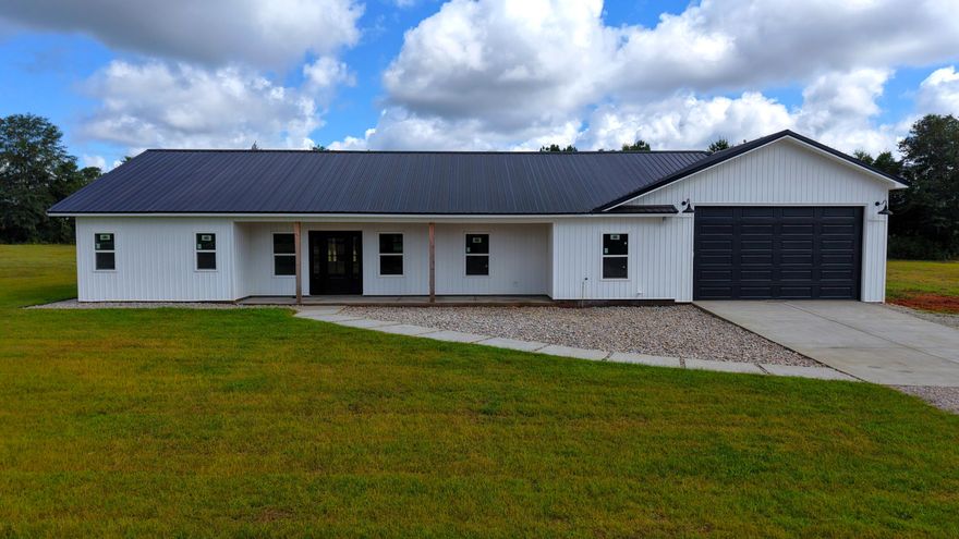 Modern Farmhouse - Over 4,000 Sq. Ft. Under Roof! This new custom house blends rustic charm with modern luxury.   Inside, the open floor plan features a vaulted 20x50 great room with exposed beams, custom soft-close cabinetry, granite counters, and black stainless steel appliances. The oversized kitchen island and deep farmhouse sink. Sleek track lighting adds a modern touch throughout.  The owner's suite is a private retreat with dual walk-in closets; a spa-style wet room featuring a soaking tub, rainfall shower, and body jets. Three additional bedrooms; a dedicated office, and custom guest bathrooms provide space for everyone. Step out onto the 12x60 poplar-lined covered porch with cedar accents, recessed lighting, and ceiling fans--perfect for relaxing or entertaining.  Quality Finishes