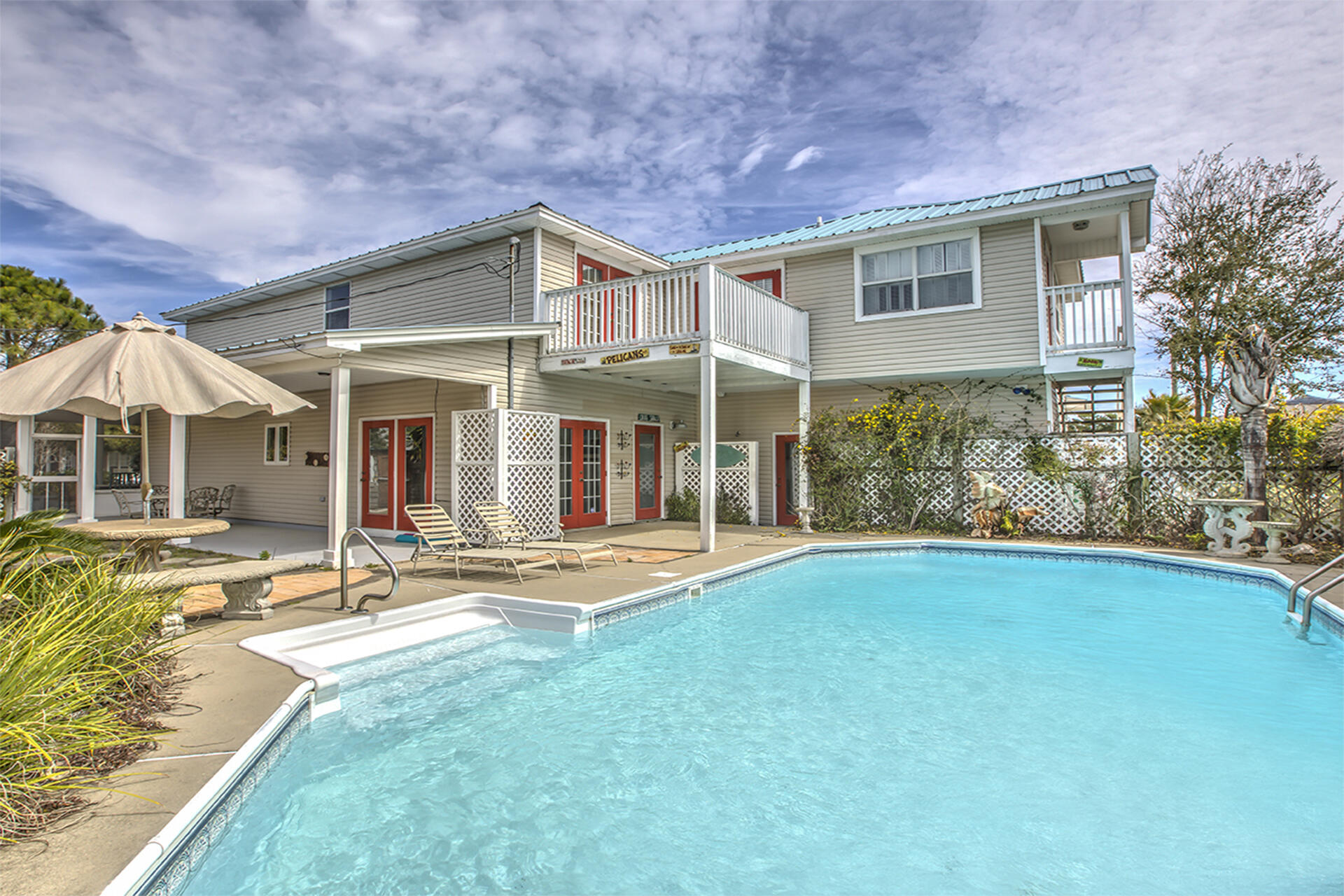 This four-bedroom home offers a great location in Crystal Beach, which places you within walking distance of the emerald waters of the gulf. The two-story home is surrounded by a white picket fence, with a walkway that leads to a wraparound, enclosed porch. Etched glass doors at the entrance open into the living area. The modern kitchen includes stainless steel appliances and bright cabinetry, accented by an ebony black countertop. Double wide arched portals lead into a formal dining room, with expansive views of the salt water pool. A guest bedroom is on the first floor with access to a full hall bath. On the second floor, the spacious master bedroom includes two walk-in closets and en suite bathroom with a walk-in shower and soaking tub.