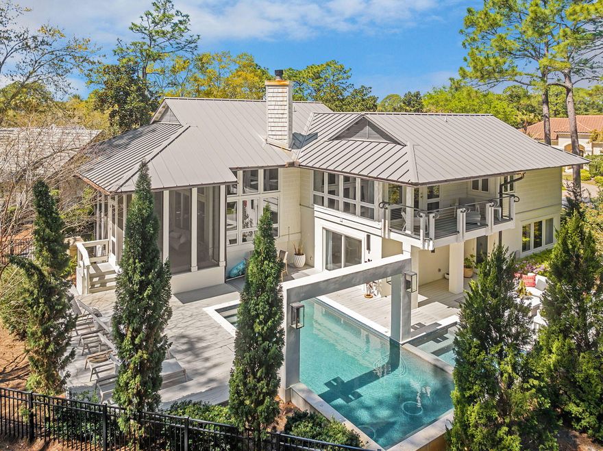 Tucked in the pines in the exclusive enclave of Burnt Pine is where you find this 2671 sf 3BR/3.5BA home. Refreshingly unique in design for the area, the simplicity of the exterior reveals a touch of modern esthetic. As you approach the entry and the fabulous oversized, custom front door with it's sleek polished nickel hardware, it is apparent you have arrived somewhere stylish. As you enter, the ''lightness'' of your surroundings is like a breath of fresh air. No garish colored walls, heavy moldings or overly ornateness here...only a soothing, sophisticated backdrop of seamless neutral color, luxurious white Peacock Paver floors and clean, uncluttered lines. Split level in design, the main living area beckons you up the stunning white stone staircase with it's gleaming elegant metal handrail, but first, stop to explore the two bedrooms located at entry level. Each bedroom has generous amounts of light and elegant private baths with Carrara marble vanities, sleek polished nickel cabinet hardware, faucets and light fixtures, and large glass-enclosed stacked white subway tile showers. Back in the entry, the hallway leads past an elegant half bath to the attached two car garage. Extra storage space is tucked neatly under the stairs. Up the half flight of steps is the light-filled main living area. An abundance of floor to ceiling windows expands the interior to the beautiful, forested out-of-doors. Perfect for entertaining and also for keeping a family close, the layout flows perfectly between living, dining and kitchen. The 14 ft ceilings showcase the dramatic limestone gas fireplace. The kitchen is absolutely stunning; uncluttered, streamlined and elegant, and outfitted with stainless Jenn Air appliances. Glistening marble tops the island and the countertop that continues high up the backsplash to gracefully accent the open shelving. Upper cabinetry and pantry is neatly disguised along a sleek, grooved wood wall, revealed only by stainless flush mount ring-pull hardware. So well crafted, you might miss one pair of doors leading to an adjacent room, ideal for a kids lounge area, bunk room home office. Close the doors and you might forget it is there. Beside the kitchen is the dining area surrounded by windows and opening to a large screened porch and deck. Up a second half level is where you find the master suite. Luxurious wool carpeted bedroom with vaulted wood ceiling, two walls of windows and one that opens to a private balcony with stainless cabled railing. The beautifully forested backyard conceals any neighbors nearby. Enter the elegant master bath to find dual marble topped, metal based vanities with top quality polished nickel fixtures and a generously proportioned walk-in shower with standing glass panel, ceiling mounted rain head faucet with wall-mount handheld. Off the master bath is one of two oversized closets located on this level. As you exit the master suite, pause to admire from above this beautiful home as it is opens to your view. Take note of the elegant details you have observed, like the  high quality recessed LED lighting throughout, fixtures, faucets, marble, cabinetry, flooring, and even the sophisticated metal trimmed vanity mirrors in all baths. There are also the valuable details not so readily apparent, like a Rinnai tankless water heater and a whole house natural gas generator. You owe it to yourself to experience this uniquely modern esthetic in exclusive Burnt Pine.