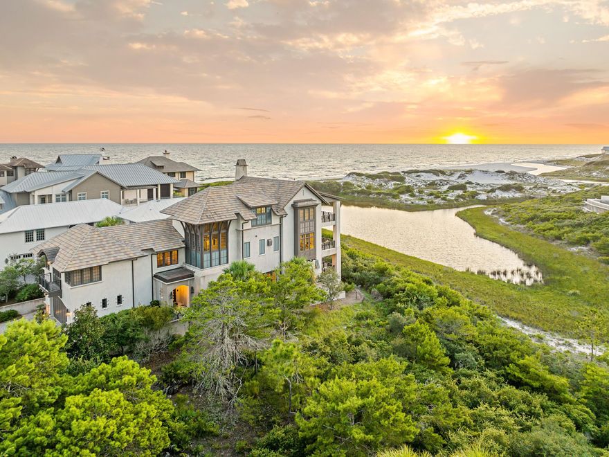 Perched on one of the most elevated lots in The Retreat, this exceptional residence offers a vantage point unlike any other along Scenic 30A. From its commanding position, the home unveils a rare panorama of Draper Lake, one of Florida's treasured coastal dune lakes, framed by the sculpted white dunes and the endless horizon of the Gulf. The layered beauty of lake, dunes, and Gulf is a view almost never found -- and it sets this property apart as one of the most coveted homesites in the community. Designed by renowned architect Tom Christ and built to Fortified Home Construction Standards with steel-reinforced concrete and a concrete tile roof, it offers enduring strength paired with timeless elegance. Balconies on each level provide outdoor living space with sweeping coastal views, while the interiors combine quality craftsmanship with everyday comfort. The second floor is the heart of the home, where soaring ceilings, rich hardwood floors, and a stone fireplace anchor a warm yet sophisticated living space. A chef's kitchen stands ready for entertaining with dual islands, Thermador appliances, and quartzite countertops. The main level also includes a guest suite, office/bonus room with en suite bath, and a powder room. The third floor is devoted to a spectacular master suite, where sweeping views of Draper Lake, the dunes, and the Gulf create an atmosphere of serenity. Custom his-and-hers closets with a built-in safe, a private den with fireplace, and a secondary laundry complete this private retreat. The first floor adds three guest suites, all with en suite baths, a bright courtyard, a practical mudroom connected to an outdoor shower for quick cleanup after beach and lake adventures, and a cedar closet. Unique amenities include a climate-controlled wine room and a heated and cooled storage room large enough to serve as a personal gym or wellness studio. Beyond the home itself, this lot is recognized as one of the finest within The Retreat, a gated enclave celebrated as the most private and pristine community on 30A. Residents enjoy more than 3,000 feet of private Gulf frontage, a world-class pool and beach club, access to Draper Lake for watersports with a boathouse for kayak and paddleboard storage, and an expansive protected natural buffer that ensures lasting privacy. This is more than a home  it is a rare legacy property, blending elevated coastal living with the unmatched exclusivity of The Retreat.