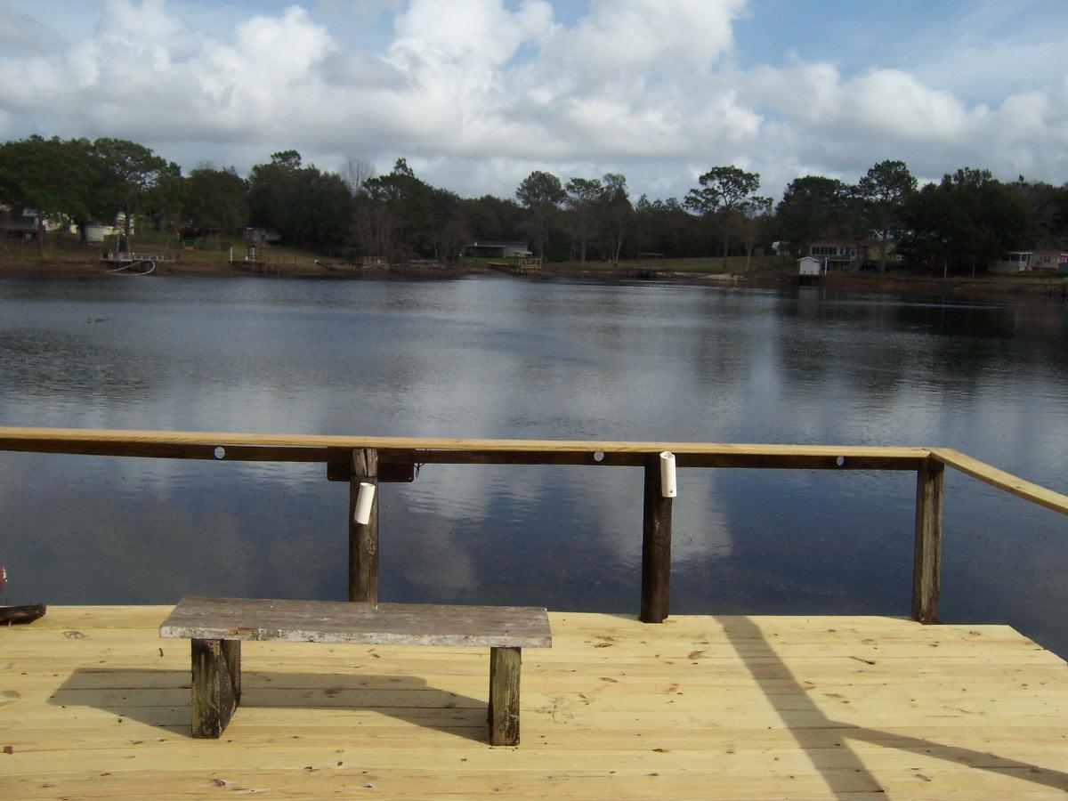 Lakefront getaway on Juniper Lake. Home has attached carport and large front porch a separate detached carport on the side and a full length Florida room and back porch. Nice storage building on the way down to the water on one side and a small shed on the other side for outside tools. Dock has just been redone and has a nice covered boat slip. Close to town and Schools. Boat ramp and nice park at the beginning of the street. Great fishing and beautiful views out your back door.
