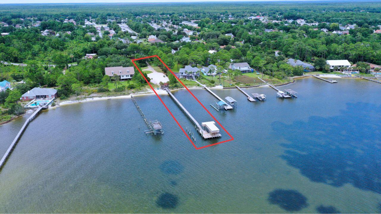 This marsh-free, wetlands-free, unencumbered 1+ acre waterfront property is comprised of approximately 100-feet of beautiful white sandy beach on the Santa Rosa Sound and 107-feet of street front land. It is an impressive 432-feet long on the east side and 418-feet on the west side (different lengths due to shoreline profile). The parcel is plenty large enough for an expansive main house and separate smaller house. The sewer tap fee has long been paid and the sewer line has already been run from the tap to the main house site, as has the main water line and natural gas line. A functioning lawn pump on an existing private well supplies a multi-zone pop-up sprinkler system. There is a long, wide cement driveway, with a turnaround, that runs from Parish Blvd. to potential main house and separate smaller house sites. Also included is a 320-foot dock with an enclosed boathouse and partially covered south end - for shady comfort and rain/sun protection while relaxing, fishing, etc. The dock's relatively deep-water south end also features a 50-foot yacht slip, covered boatlift and 2 covered wave runner lifts, as well as a covered fish-cleaning counter and sink. There is also an attractive, well-built octagon-shaped covered gazebo connected to the beach-end of this spectacular dock.
This property is located in one of the absolute most picturesque areas of the beautiful Santa Rosa Sound. The postcard-like backdrop of the Sound-front view includes a never-to-be developed, Air Force-owned barrier island covered in sand dunes made of sugar-white sand separated by aromatic native pine trees. This naturally beautiful, virtually undisturbed barrier island separates the emerald waters of the Gulf of Mexico from the calmer, pristine waters of the Santa Rosa Sound. Just imagine a rare natural waterfront view of the Sound and barrier island that will never be contaminated by high-rise condominiums.
The location of this large waterfront property on Parish Blvd. takes you away from the hustle and bustle of noisy U.S. Highway 98. This quiet location away from Hwy 98, combined with the fact that the vessel navigation channel is located on the opposite side of the Santa Rosa Sound, makes for one of the most tranquil and majestic waterfront settings in south Okaloosa County, if not all of Northwest Florida. This is the perfect property to buy and build your forever dream home. There is an ever-diminishing, finite amount of waterfront properties available in Okaloosa County and an even more finite number of waterfront properties of this caliber. Notably, Parish Point, a waterfront subdivision first developed around the year 1980, is one of the last waterfront subdivisions in south Okaloosa County, if not the last, to feature 100-foot-wide waterfront lots on the Santa Rosa Sound. Don't miss out on this golden opportunity to own a piece of Northwest Florida heaven!