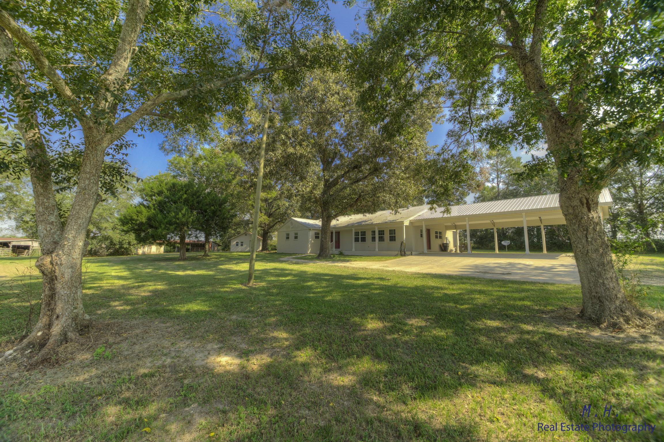 You will fall in love with this country estate. Completely remodeled 3 bedroom brick home w/metal roof, 75 acres w/rolling pastures, multiple barns 21 horse stalls, over 20 pecan trees, and a stocked bass pond. 1 hour from beaches. Perfect for hunting, fishing, organic farming, horses or livestock, weekend getaway or full time living. Home has been rebuilt from the block foundation. Open floor plan, cook's delight kitchen - all wood cabinets, granite, stainless steel appliances and induction oven. Hand scraped laminate wood flooring throughout, tile in wet areas, lots of storage, office and large utility room. Upgraded bull nose corners, recessed lighting, pendant lights. Enjoy quiet evenings sitting on your expansive screened back porch, waiting for a deer and wildlife to walk