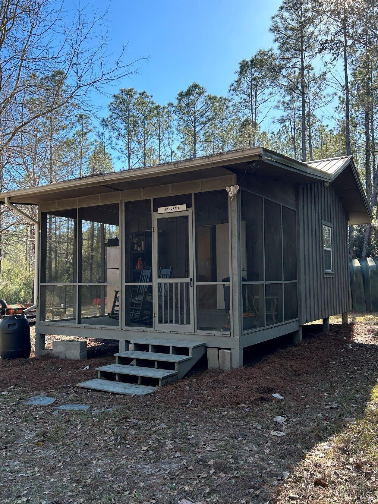 UNDER CONTRACT and accepting back up offers. Intrigued with living off the grid, or glamping at the next level? This 12.5-acre lot is located in the gated recreational subdivision of Walton Plantation. Approximately 3 acres are cleared land. The property comes complete with a 256 square foot board and batten cabin. Features include a propane heater w/ wall mounted thermostat, propane stove and cooktop, propane refrigerator, propane on demand water heater, propane tank, gas generator, electric window AC, microwave, composting toilet, 300 gallon water storage tank, water pressure tank with 12v water pump, shower, sink and ceiling fans. Walton Plantation is a private community and includes hunting, fishing, a chapel for gatherings, community well and dumpsters for trash disposal, restrooms, ponds, garden, horseback riding and ATV trails. Owners may join the hunt club for an additional fee, allowing access to approximately 2,000 acres. Info is believed to be accurate but should be verified. Ditch the sports car and jump in your 4 wheel drive to escape to your own paradise in the pines. Zoning for parcel is 1-acre SFR and 11.5 AC Non-Ag.