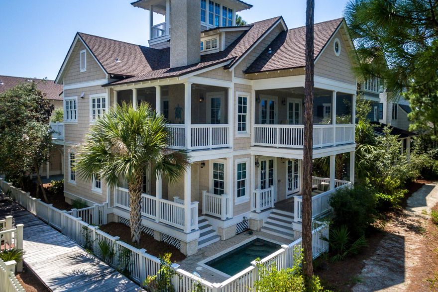 Distinguished by its wood cladding, this classic 3,443 square foot beach retreat combines contemporary architectural influences with historic New England born aesthetic found in the exclusive Gulf front community of WaterSound Beach. This four-story beach house is located just down from one of the winding wooden footpaths that leads to the sugar white sand and emerald waters of the Gulf along WaterSound's private beaches. Boasting warm heart pine wood floors throughout, the main floor living room wrapped in shiplap features double doors that open up to a covered rear porch with comfy outdoor furniture and a heated jacuzzi pool overlooking Yacht Pond. Off of the living room is an oversized bedroom with an ensuite bath that offers access to the covered back porch. The main floor master suit