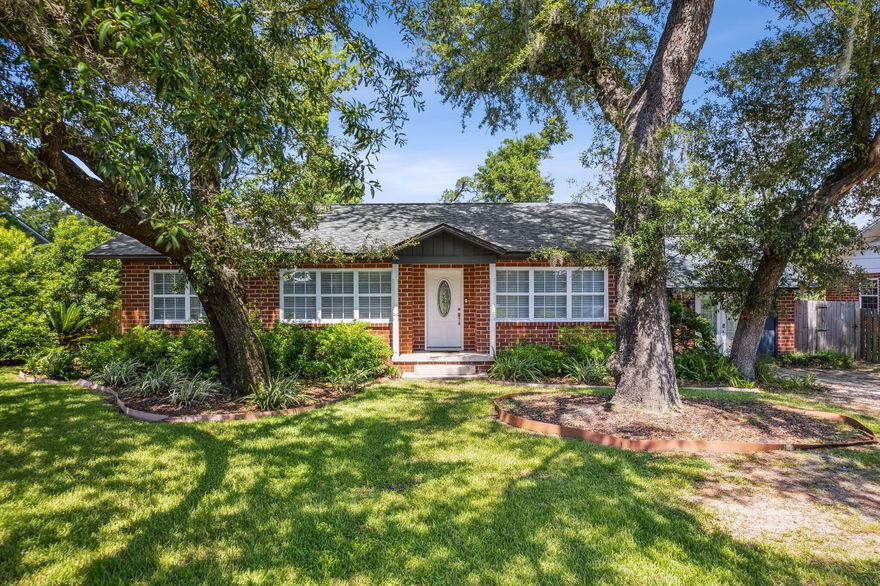 Welcome to this delightful brick home at 1603 Dewitt Street in Panama City's cherished Cove neighborhood-- all set for you to move in and enjoy. As soon as you enter, the living and dining area welcomes you with its bright and open feel. Generous windows and French doors open to a deck that extends your living space into a green backyard paradise. Just off the living area is a cozy space featuring a fireplace, window seat, and custom shelving, perfect for relaxing. The kitchen features white farmhouse cabinets, contrasting beautifully with quartz countertops and stainless steel appliances. And, for your convenience, a multi-purpose laundry room also serves as a mudroom with backyard access.