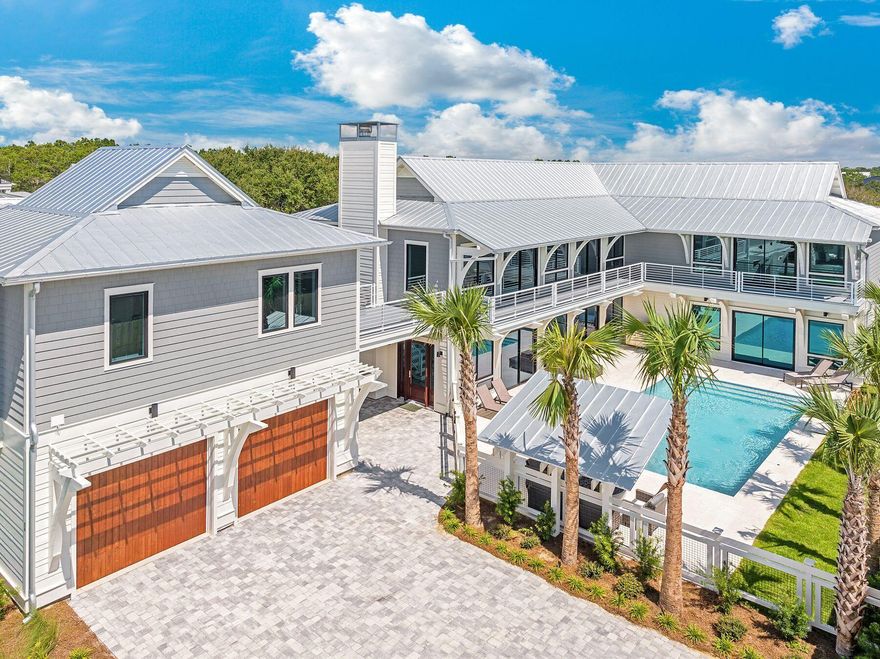 Located on 30A between Alys and Watersound and just a block from the beach, this newly completed home is brimming with quality features, from hardwood flooring and coffered ceilings to shiplap walls and textured tiles. Uniquely designed as a two-story residence, this home offers a more accessible, livable layout than others without sacrificing space or luxury. The broad paved driveway provides a grand approach to the main home and carriage house above the two-car garage. Thoughtfully built as an attractive second home or investment property, it caters to those seeking easy one-story living, generous closets, and open entertaining spaces. This well-appointed beach house is perfectly designed around the courtyard, pool, and gas fire pit. The open family room is focused on pool views with expansive windows introducing abundant natural light. The deep coffered ceiling with grained wood inserts and crushed shell fireplace add additional warm touches to the home. Enter the chef's kitchen, which is superbly appointed for entertaining with a farmhouse sink, dual dishwasher, two side-by-side refrigerators, a 48" gas range, and butler's pantry complete with beverage cooler and prep sink. Under-cabinet lighting, wall sconces and textured tiles add additional luxury touches to spaces throughout the home. Two primary suites include one on each floor. The first-floor suite has an enviable walk-in closet/dressing room with built-ins. Doors open directly onto the pool. A sliding barn door hides the magnificent master bathroom with dual vanity. A wet room-style shower has two separate shower heads and an oval soaker tub within the glass-enclosed space. The second-floor master suite is similarly spacious, with another custom walk-in closet and a huge shower with dual heads. Doors open onto the lengthy wraparound balcony, providing a space to quietly read or watch sunsets. An additional six bedrooms including a bunk room offer versatility. Upstairs the generous media room complete with sconce lighting is a great space for a group to watch movies, play games, or just relax together. Stairs from the terrace lead up to the guest house above the garage. It includes a kitchenette, sitting room, two bedrooms and a bathroom, ensuring guests are comfortably accommodated. The quarter-acre landscaped grounds include the 30X15 pool, a sitting area with fire pit and a cantilevered gazebo, providing a shady place to relax. Make this your family's beach retreat or a coastal investment. Either way you'll love calling this extraordinary 30A property home.