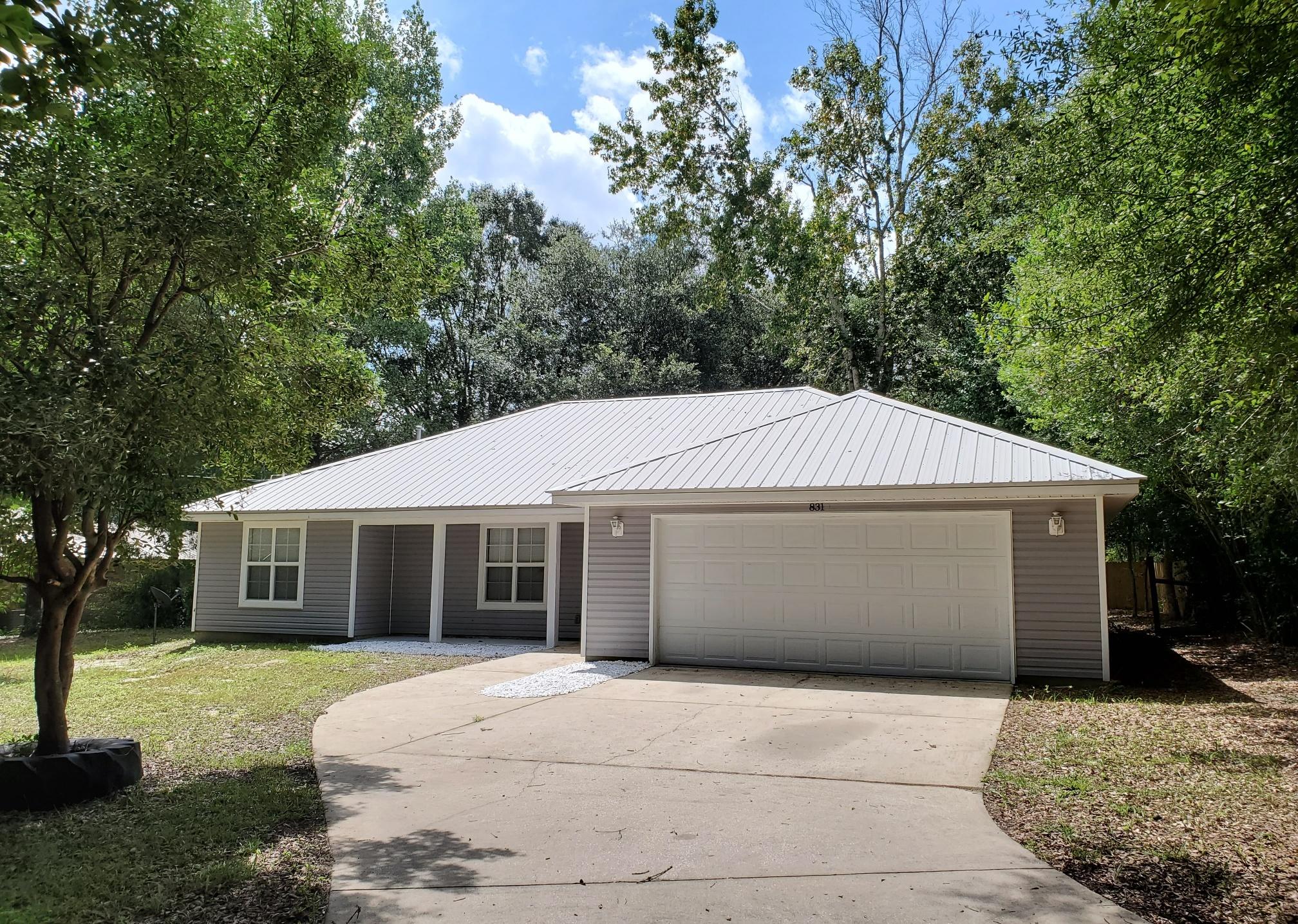 Welcome home! Adorable 3 bedroom 2 bath for sale in Crestview! This property features a large wooded front lot, offering lots of privacy. Long driveway leading to a two car garage and open front porch. Beautiful decorative metal roof. Large, wide open floor plan in the main living areas with tons of recessed lighting and tall ceilings. Spacious island in the kitchen with lots of cabinet space and beautifully upgraded granite countertops. Pantry. French doors off of the dining area lead to a huge, open back yard and back porch. The yard features a privacy fence and a concrete pad that could be used for boat or trailer storage, or the foundation for a storage building. Split bedroom layout for added privacy. HUGE indoor laundry room. Large master suite with walk-in closet and shower.