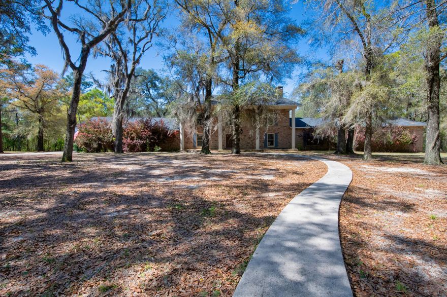 This gorgeous Antebellum style home is situated on a one of a kind property featuring beautiful mature oak trees draped in Spanish moss.  Five acres has being surveyed out to convey with the home. The large, unique residence and the detached workshops and garages are all constructed of genuine Old Chicago brick. Last appraisal lists the main house as having 7072 square feet of living area. Besides the five bedrooms there is an upstairs playroom or study.  Three bedrooms are upstairs and two are downstairs. Beautifully remodeled kitchen features all new cabinets, granite counter tops and Wolf and Subzero appliances. Large formal dining room and very roomy breakfast room with a picture window that overlooks the 24x48 gunite pool and the woods to the rear.  Deer and wildlife abound!!