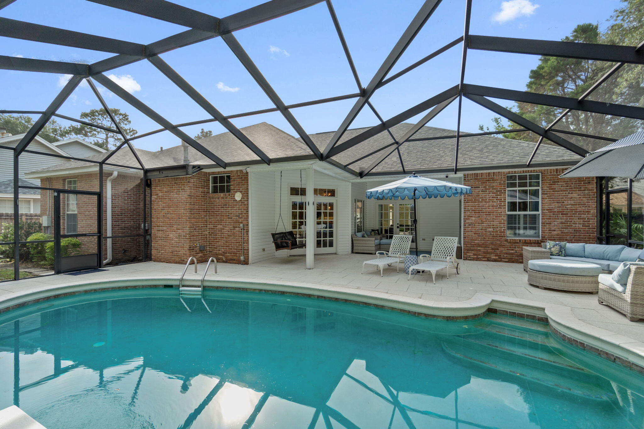 Welcome to your dream pool home in the desirable gated Niceville community of Parkwood Estates! This beautifully updated 4-bedroom, 3-bath home sits on one of the largest lots in the neighborhood at the end of a quiet dead-end street, offering privacy and a serene wooded backdrop with all features and high end finishes you've been looking for. Pull up to the long driveway and immediately fall in love with this brick Florida charmer complete with a covered front porch, palm trees, and mature tasteful landscaping. You'll love coming home because when you enter the front doors you'll look straight ahead to the stunning backyard oasis, but inside you'll find a spacious split floor plan complete with two living rooms and a formal dining room. Appreciate this fully and recently renovated kitchen sure to be your family chef's delight featuring a Cosmo professional gas range, French door stainless refrigerator, stunning copper range hood, tile backsplash, quartzite countertops, drop down pendant lighting, and recessed lighting. Open to the kitchen is a family room with lovely shiplap ceiling adding the perfect touch of coastal charm, and popcorn ceilings have been removed for a modern feel. The owner's suite is an oversized room with a trey ceiling and additional sitting area with doors to the backyard pool. There are two walk-in closets, a separate shower, jetted tub, and double vanities. The other 3 bedrooms are great spaces from built-in bookcases to new carpet (don't miss the extra storage above the closet doors!) and you'll love the updated full bathrooms.
Step outside through either set of French doors to the ultimate entertainer's paradise where you'll enjoy an enclosed, heated gunite pool within a massive screened patio with a gazebo, outdoor kitchen area with natural gas hookups, and a separate fenced kids' play area all within the fully fenced in backyard. The pool deck has been resurfaced with beautiful seashell pavers and there's more than enough room for all your outdoor furniture to accommodate backyard get togethers! This is truly the best of Florida living where you will love making memories! Additional updates include a new water heater (2025), HVAC (2023), and roof (2017). This home offers style, function, and unmatched serene outdoor living - all in one of Niceville's most desirable neighborhoods.