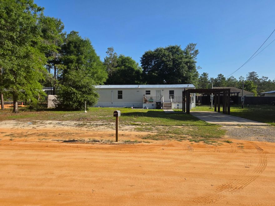 2BR/1BA manufactured home on an oversized 0.46-acre homesite in DeFuniak Springs, comprised of two 0.23-acre lots. Built in 2006 with an efficient 864 SF layout and over $45K in upgrades completed in 2024, including commercial-grade LVP flooring, a mini-split system, deck, galvanized metal roof, gutters, and a new septic system.

Outside features include a carport with additional covered parking, multiple sheds, and a workshop with power, ideal for projects or extra storage. The second 0.23-acre lot includes a septic tank and existing public water and electric hookups already in place, making it perfect for RV parking, future use, or potential resale. Seller will remove the shipping containers at buyer's request. *Information is believed to be accurate. Buyer to verify all information.