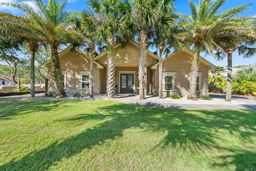 Rare bay-front opportunity in the established Hatchee Shores community of Santa Rosa Beach. Set on nearly half an acre with 100 feet of bay frontage, this beautifully maintained home offers 3 bedrooms, 3 bathrooms, and an open floor plan designed for effortless coastal living. A canopy of mature palms frames the stucco-and-stone exterior, with a brick paver driveway and elegant double glass entry doors flanked by stone columns. Inside, enjoy hardwood and tile floors throughout, crown molding, recessed lighting, and a dramatic stacked-stone fireplace anchoring the great room. The primary suite offers a spa-inspired ensuite with soaking tub, dual vanities, stone countertops, and a walk-in tile shower.  Step outside to a covered back porch shaded by grand live oaks, then walk to your private dock where breathtaking open bay views stretch to the horizon - perfect for fishing, boating, or simply watching the sunset. Additional highlights include a large detached workshop/storage building, outdoor shower, carport, and attached garage. Ideal as a primary residence, second home, or income-producing investment. Minutes to the sugar-white beaches of 30A, premier dining, and upscale shopping.