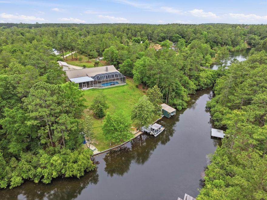 Peaceful lakefront living on beautiful spring fed Mirror Lake! This stunning home offers the perfect blend of privacy, comfort and outdoor living just 7 miles from town and close to military bases. Quiet country living without sacrificing convenience. Inside features a huge chef's kitchen, spacious living areas, and breathtaking lake views. Step outside to your private oasis with a heated screened swimming pool and beautiful cage enclosure overlooking the sparkling lake. The property includes a covered patio, large barn, RV pad with 50-amp hookup, irrigation system with pump house, greenhouse, orchard, and raised flower beds. Waterfront features include a boathouse, boats with kayaks included plus a dock. Watch the video & you'll see this incredible property truly has it all!
