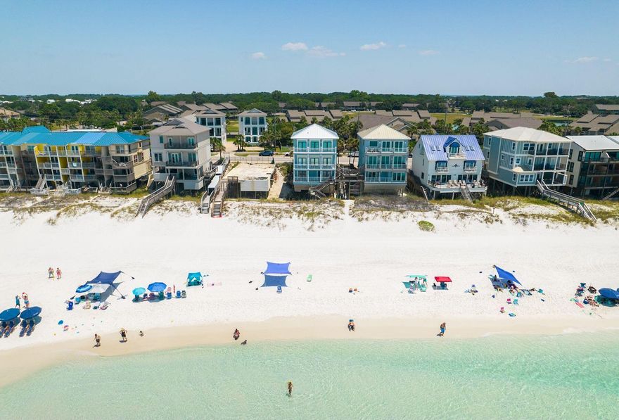 Set directly on the sugar white sands of the Emerald Coast, this exceptional Gulf front residence offers a rare blend of refined coastal living and proven investment performance. Spanning three levels, each with expansive south facing decks suspended above the dunes, the home captures uninterrupted panoramic views of the emerald waters from sunrise to sunset. Thoughtfully reimagined from the studs out, the property reflects a clean, sophisticated design with a new roof and professionally curated interiors. Paved parking for four vehicles ensures effortless arrival, while direct beach access invites a seamless connection to the shoreline. The first level is designed for both comfort and flexibility, featuring two Gulf front bedrooms with immediate access to the lower deck and private beach path. A dedicated media lounge with wet bar and refrigerator creates an ideal retreat for guests and extended stays. On the second level, a wall of glass frames sweeping 180 degree Gulf views, filling the main living space with natural light. The open concept design flows effortlessly from the spacious living area to a defined dining space and into a chef's kitchen appointed with stainless steel appliances, custom cabinetry, and granite surfaces that extend into an inviting breakfast bar. Three sets of French doors open to a generous balcony, offering a front row setting for coastal breezes and evening sunsets. A fully equipped home theater enhances the experience for both relaxation and entertainment. The third level serves as a private sanctuary, anchored by a Gulf front primary suite designed for quiet retreat. The spa inspired ensuite features dual vanities, a walk in shower, and a freestanding soaking tub. Two additional guest bedrooms, including a thoughtfully designed bunk room, complete the level. Beyond its design and setting, the home presents a compelling investment opportunity. With no HOA and a strong rental history, the property generated $181,000 in revenue in 2025, with $143,000 already secured for 2026 and projections approaching $235,000 annually. Its five bedroom configuration and beachfront positioning continue to support consistent demand and income potential. Ideally located near premier shopping, dining, golf, and entertainment, including proximity to Silver Sands Premium Outlets, this is a rare opportunity to own a Gulf front property that balances lifestyle, design, and performance with ease.