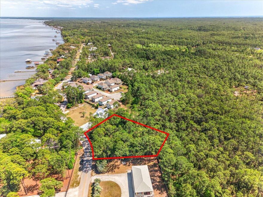 This wooded corner lot offers a beautiful setting to build your future home, with Choctawhatchee Bay directly across the street! Surrounded by natural landscape, the property provides a peaceful, coastal feel while still being conveniently located. With no HOA, you have the flexibility to design and build to suit your vision without restrictive guidelines. This lot sits in a quiet, well established neighborhood - perfect for families! Utilities including water, sewer, and power are available, and a survey is already on hand. Enjoy multiple Gulf beach accesses all within a 15 minute drive (Blue Mountain Beach, Ed Walline, and more)! Kellogg Bayside Park is just 0.2 miles away, offering easy bay access for kayaking, paddleboarding, and canoeing, along with a fishing area, picnic tables, and an outdoor shower. Just 1.6 miles away, Cessna Landing features a public boat launch, docks, picnic shelters, basketball and squash courts, and a playground. Convenience meets location with South Walton Publix, dining, and everyday essentials only minutes away. Situated just north of Chat Holley Road and Highway 98, this property offers easy commuting while keeping you close to the water and all the area has to offer!