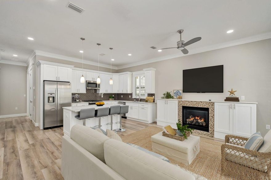 A rare opportunity to own a thoughtfully designed, recently built residence that prioritizes both comfort and ease, this single-story home offers a level of refinement seldom found at this price point. Completed in 2023, the property reflects intentional design choices and elevated finishes throughout. Inside, ten-foot ceilings and plantation shutters set a polished tone, while the open-concept layout creates a natural flow between living, dining, and kitchen spaces. A built-in gas fireplace framed by custom cabinetry anchors the main living area, adding warmth and architectural interest. The kitchen is equally impressive, featuring quartz countertops, a gas range, stainless steel appliances, and a generous workspace designed for both everyday living and entertaining. Both bedrooms are privately positioned at the rear of the home, each with its own ensuite bath, privacy windows, and direct access to the outdoor living area through sliding glass doors. The bathrooms are beautifully finished with custom tilework and frameless glass showers, and include a tub-and-shower combination in the secondary suite. A well-appointed laundry room includes additional cabinetry, a utility sink, and a washer and dryer that remain with the home. Outdoor living is equally considered, with a spacious paver patio designed for relaxing afternoons and casual gatherings. A retractable awning extends across the patio, offering shade on warmer days, while a fully fenced yard enhances privacy. Additional upgrades include a water filtration system and a Generac generator, providing both comfort and peace of mind. The home also features a one-car garage with space for storage or a golf cart, complementing the community's golf-cart-friendly design. Residents enjoy access to a gated entrance, a well-maintained community pool with covered seating and facilities, and a cohesive neighborhood atmosphere supported by low HOA fees and the absence of short-term rentals. Positioned just minutes from premier shopping, dining, and multiple beach accesses, this residence offers a refined take on low-maintenance coastal living with modern conveniences already in place.