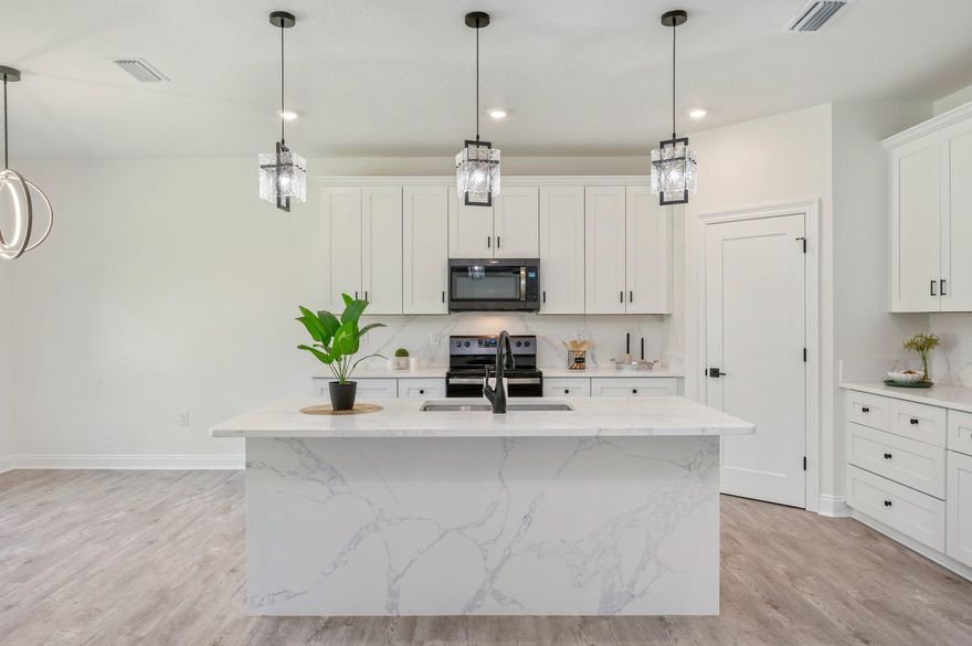 Step into elevated new construction with this impeccably designed residence by a local, VA-approved builder. Thoughtfully curated finishes include seamless luxury vinyl plank flooring throughout, granite countertops in the kitchen and baths, designer lighting, and upscale fixtures that create a polished, cohesive aesthetic. The open-concept layout flows effortlessly, ideal for both everyday living and entertaining. A stainless-steel refrigerator is included for added convenience. Exterior highlights include modern black gutters, a full irrigation system, and a privacy-fenced backyard. Enjoy tranquil mornings on the covered front porch or unwind on the spacious covered back porch with ceiling fan. Move-in ready with timeless, elevated finishes throughout.