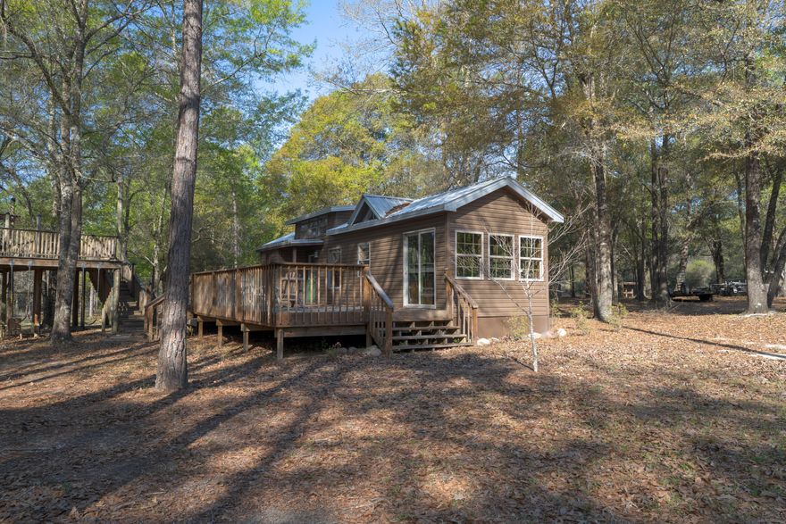 Turn-key retreat complete with utilities, cabin, massive metal garage, outdoor kitchen, Fireplace, 300 fruit trees, irrigation, 300' zip-line, ATV trail, and more! Cabin 2013, extra roof overhangs 2020. Primary bedroom downstairs with a loft upstairs. Full bath inside with extra half bath on the deck. Septic system capacity designed for a 5000 square foot home, with RV septic and electric hookups. 500 gal underground propane tank. Over 300 fruit trees including, Blueberries, Apples, Peaches, Plums, and many more. Walton plantation is a private gated community. Owners enjoy 2500 shared acres including a communal garden, chapel, fishing pond, Horse and ATV riding trails, and 300 yds of shooting ranges. Join the hunting club for access to 2000 acres of beautiful land!