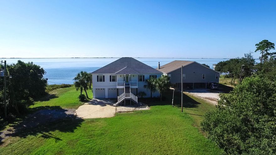 IMPROVED PRICE! Magnificent Water Views! Large, expansive doors and open floor plan allow for a never ending view of the Intracoastal Waterway. This 3 bedroom/2 bath home boasts a desirable split bedroom floor plan with appealing tile throughout. A cathedral ceiling in the Great Room, Kitchen, and Dining area expands the open and airy feel of the home. The kitchen features beautiful Granite Countertops with breakfast bar, Stainless Appliances and pantry for convenient storage. A two filter whole house water filtering system reduces chemicals and minerals and delivers softer water to every faucet. All windows and doors have been custom fitted with steel, Accordion Hurricane Shutters. The essence of water front living is enhanced with a 200 ft dock and covered 10,000 lb Boat Lift complete with water, electric and breaker box.  Additionally, all stairs, the covered front porch and the full length veranda are composite maintenance free Trex decking with clear view porch railing to not obstruct the view.  The fully enclosed lower level is accentuated with 3 garage doors for cars and boat storage, an enclosed storage area and is designed with blow out walls.  RV parking, cement pad with separate 30 amp RV plug.  The lawn pump for the sprinkler system is 3 years old.