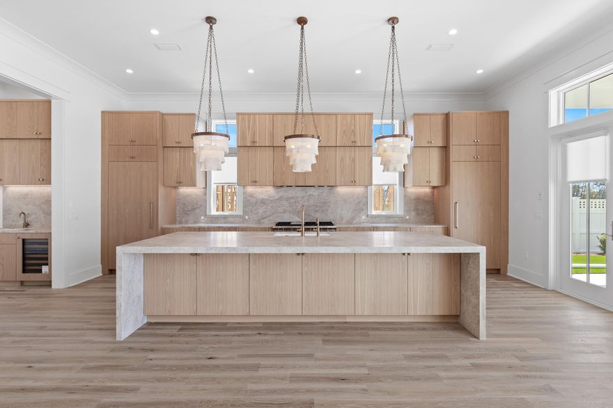 Currently in framing! April progress photos coming next week.

The Darien III by Romair is a custom residence with a detached carriage house, offering 4,775 square feet, 5 bedrooms, 5 bathrooms, 2 half baths, and a 2-car garage, located on a Homesite backing up to vast dry pond area in Powell Landing East at Watersound Origins.

The first level is arranged with clearly defined spaces, beginning with a dedicated dining room that includes a built-in wet bar and undercounter wine refrigeration. The kitchen is positioned at the rear of the home, opening directly to the covered porch and summer kitchen, creating a direct connection to the outdoor living areas and pool courtyard . The adjacent living room features a fireplace and 16 foot slider doors that open fully to the exterior, extending the living space outward. Twelve-foot ceilings throughout the main level reinforce the scale of each space without sacrificing proportion.

The owner's suite is located on the main level with French doors leading directly to the pool and spa. The bath includes a walk-in shower with upgraded rain fixture shower head and free-standing soaking tub, along with a spacious custom closet designed with a center island for additional storage and organization .

Functional spaces are equally considered. The laundry room includes built-in cabinetry, a sink, a dedicated broom closet, and a bench with cubbies for everyday use. Circulation between the garage, mudroom areas, and main living spaces is efficient and separate from guest-facing areas.

The second level provides additional bedrooms and a secondary living space, offering separation from the main level while maintaining connection through a central stair hall. Ten-foot ceilings continue throughout the upper level, maintaining consistent volume and scale. Above the garage, the carriage house includes a kitchenette, living area, bedroom, and bath with its own access, suitable for guests or extended stays.

The outdoor environment is fully integrated into the plan. A heated saltwater pool and spa with baja deck are set within a paver pool deck and enclosed by fencing, all managed by a WiFi-enabled pool controller. The cabana with fireplace anchors the space, while the dedicated outdoor kitchen connected to the main house is equipped with an Artisan grill with stainless steel doors, U-Line outdoor refrigerator, and sink.

Interior finishes include white oak cabinetry with stained overlay throughout, along with upgraded quartz surfaces and upgraded Delta plumbing fixtures. The home is equipped with a Water and Air Wellness Package, including a whole-house water softener, reverse osmosis system, REME Halo air cleaner, and an added integrated leak detection system.

Additional features include a tankless water heater and detailed interior trim consistent with the overall architectural design.

Estimated completion:  2026

As part of Watersound Origins, often called "A Coastal Village," residents relish abundant amenities like the Village Commons resort-style pool, fitness center, sports courts, miles of nature trails, event lawns, and the Origins Golf Course. Surrounded by towering pines and just minutes from Lake Powell and the beaches of Scenic Highway 30A, this community blends natural beauty with easy access to Inlet Beach, Grayton Beach, and beyond. Upcoming highlights include the 15.5-acre Longleaf Art Park, opening in 2027, featuring cultural and recreational experiences.