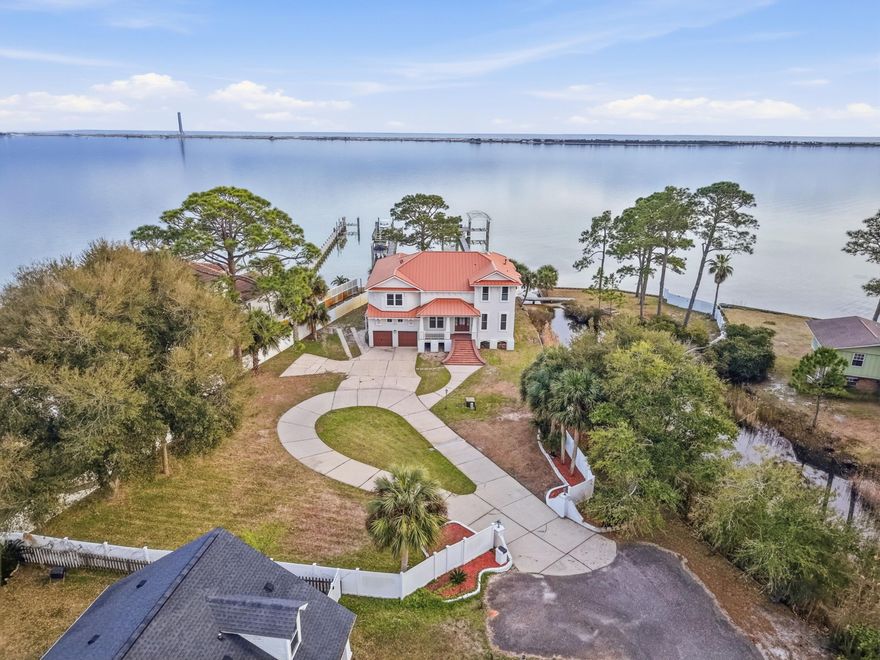 At the edge of the Intracoastal waters of Santa Rosa Sound, this elevated coastal contemporary residence offers exceptional privacy and sweeping waterfront views. Positioned at the end of a private street in Mary Esther, the home is bordered by the sound and framed by stately brick column entry walls.

Inside, five bedrooms, two bonus rooms, three full baths, and one half bath are thoughtfully arranged to maximize natural light and panoramic water views. Nearly every room overlooks the sound, allowing the waterfront to shape daily living. The main level features a gracious foyer and staircase leading into a living room where expansive windows frame the water as an ever-changing backdrop.

The kitchen is designed for entertaining with abundant cabinetry, a chef's pantry with space for a secondary refrigerator, smooth-top cook surface with double ovens, and a prep sink within the island. From the kitchen and dining areas, 180-degree views stretch across the water.

Upstairs, the primary suite offers elevated vistas, a walk-out Juliet balcony for coastal breezes, a private fireplace, and a spacious en suite bath with double vanity, garden tub, separate shower, private water closet, and extensive walk-in closet.

Outside, white-sand shoreline access extends just beyond the backyard. A private dock spans more than 200 feet and includes an 18,000-lb boat lift, 4,000-lb lift, and jet ski lift -- creating effortless access to the calm waters of the sound.

Significant 2022 improvements include a new copper roof, upgraded insulation, refreshed stucco siding, fresh exterior paint, and hurricane-rated windows.

Conveniently located between Fort Walton Beach and Navarre along the Emerald Coast, the property offers easy access to Hurlburt Field, Eglin Air Force Base, and Highway 98 while maintaining the tranquility of a private waterfront setting.