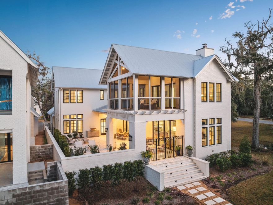 Set within the gates of Churchill Oaks, this thoughtfully designed residence captures peaceful bayou views and a level of craftsmanship rarely found. Architectural details such as arched doorways, a vaulted two-car garage, and decorative rain-chain downspouts establish the home's distinctive character, while light oak flooring, Restoration Hardware lighting, and a grand motorized foyer chandelier create a refined, welcoming interior.
The well-conceived floor plan balances everyday functionality with elevated design, featuring a butler's pantry, boot room hallway, and a stylish guest bath with designer wallpaper. A first-floor junior suite offers comfort and privacy, complete with an elegant ensuite bath showcasing an oval soaking tub, dual vanities, and a frameless glass shower. At the center of the home, the open-concept kitchen is both striking and highly functional, appointed with floor-to-ceiling cabinetry, quartz countertops, a contrasting wood and white granite island, and premium Wolf and Sub-Zero appliances, including a six-burner gas range. The adjacent dining area with wet bar flows seamlessly into the living room, where wood-beam ceiling details and a gas fireplace create a warm yet sophisticated setting. Expansive sliding glass doors open to a spacious terrace designed for year-round enjoyment, complete with outdoor heating, electric screens, and a plunge pool with a tranquil water feature.
Accessible by private elevator, the second level includes two beautifully appointed guest suites and a vaulted primary suite designed as a true retreat. The spa-inspired bath features a frameless glass shower and a custom dressing room with extensive built-in storage, while a private screened porch offers sweeping views of Hogtown Bayou and the surrounding natural landscape.
Churchill Oaks is an exclusive 40-acre gated waterfront community with just 87 homesites, offering residents access to a deepwater marina, waterfront clubhouse, three resort-style pools, fitness center, and outdoor gathering spaces. The result is a lifestyle defined by privacy, natural beauty, and effortless access to boating and the best of the Emerald Coast.