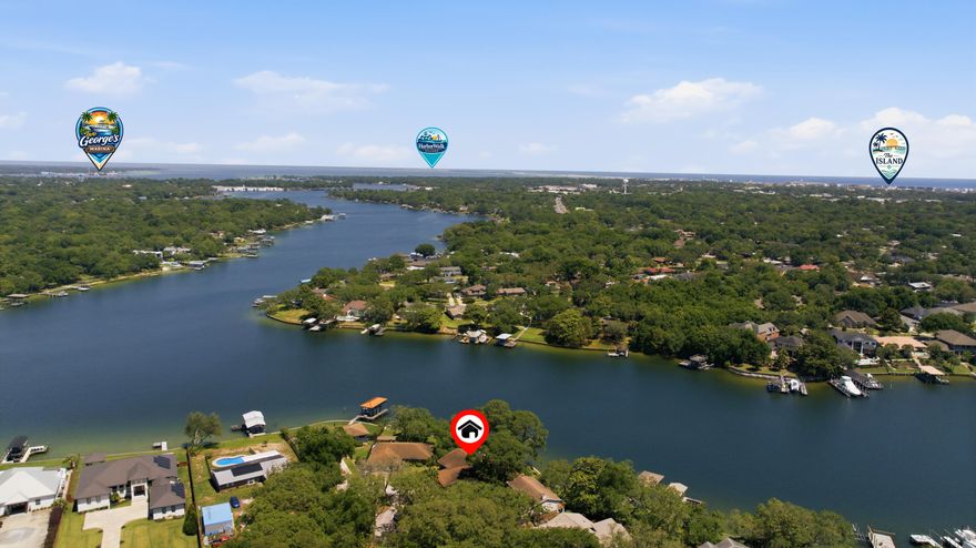 602 Cinco Terrace presents a rare waterfront opportunity with approximately 122 feet of protected bayou frontage while sitting well above the waterline, helping keep flood insurance costs significantly lower than many comparable waterfront properties. The home offers exceptional expansion potential with approximately 1,000 additional square feet ready to be incorporated into the existing footprint. A previously constructed and framed staircase location is already in place to seamlessly connect the upstairs living area to the unfinished lower level, creating a blank canvas for additional living space, guest quarters, an entertainment area, workshop, or custom design. Plumbing infrastructure for a future bathroom has already been planned with a drain line installed beneath the slab, simplifying future improvements without the need to disturb the concrete.

Inside, the home blends original character with modern updates. Fresh interior paint, updated lighting, and new luxury vinyl plank flooring throughout the living spaces, hallways, and bedrooms create a clean, contemporary feel while complementing the home's natural architectural features. Rich wood tones and stylish color-drenched interiors bring warmth and cohesion throughout the living spaces, creating an inviting waterfront atmosphere with timeless appeal. Popcorn ceilings were also removed throughout the home and garage in 2026, further enhancing the updated presentation.

Beyond the cosmetic improvements, the property has undergone substantial functional upgrades focused on durability, efficiency, and long-term peace of mind. Hurricane shutters were added to the windows, while the original asphalt roof was replaced with a metal shingle roofing system designed for longevity and enhanced weather resistance. In 2025, all exterior doors were upgraded to hurricane-rated doors with warranty documentation available. The kitchen was also refreshed with a full suite of Bosch appliances, pairing modern performance with the home's cohesive design aesthetic. Additional improvements include professionally cleaned and resealed grout in the bathrooms, kitchen, breakfast area, and office, along with updated ceiling fans and fixtures throughout the home.

Outdoor living was thoughtfully expanded to maximize the waterfront setting. The upper deck and lower concrete patio were widened to create more usable entertaining space, while a screened room was added to the upper deck to provide a comfortable year-round outdoor retreat overlooking the bayou. The lower level was further enhanced with expanded concrete flooring supported by CMU retaining walls, adding flexibility for storage, workshop space, hobbies, or future buildout potential. A dedicated photography darkroom also adds a unique creative element rarely found in comparable properties.

The mature landscaping creates a layered waterfront setting that blends native Florida vegetation with ornamental and edible plantings. Established live oaks, palms, palmettos, pine trees, ferns, agave, and American beautyberry provide natural texture and privacy throughout the grounds. Flowering additions including crepe myrtle, hydrangea, Rose of Sharon, fringe flower, amaryllis, caladium, fatsia, and crinum lilies introduce seasonal color and depth to the outdoor environment, while edible plantings such as banana trees, kumquat, fig, olive, and ginger further enhance the property's coastal garden atmosphere. A landscape irrigation system supports the grounds, and the home has also been converted from septic to county water and sewer for added convenience and reliability.

Positioned in Fort Walton Beach, the property offers convenient access to both Hurlburt Field and Eglin Air Force Base, making daily commutes efficient for active-duty military personnel, contractors, and civilian employees alike. White-sand Gulf beaches, waterfront dining, marinas, and the broader Emerald Coast lifestyle are all within close reach, allowing the property to balance privacy and waterfront living with accessibility to the area's most sought-after amenities.

602 Cinco Terrace delivers a compelling combination of protected waterfront frontage, elevation advantages, meaningful structural upgrades, future expansion flexibility, and a location that continues to remain highly desirable along the Emerald Coast. Buyers looking for a property that offers both immediate enjoyment and long-term potential will recognize the value, versatility, and lifestyle this waterfront home provides from the moment they arrive