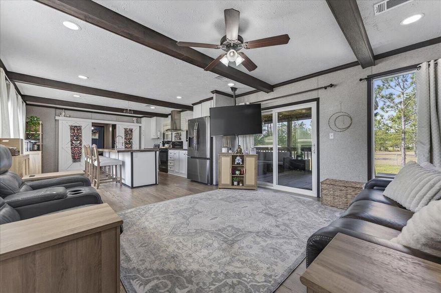 This home sits on 1.6 acres and is located just 25 minutes from Navarre Beach! Set on a quiet, well-maintained street and conveniently positioned just off Highway 87 with easy access to I-10, it offers a central location while still providing a peaceful, more private setting. The property features a spacious lot with mature pine trees and a fenced portion just off the home - great for pups! Inside, you'll find a neutral color palette, new 2024 flooring throughout, recessed lighting, and wood ceiling beams that add warmth and character. The open living and dining area creates an easy, functional flow for everyday living. The kitchen includes a large island with a breakfast bar along with ample cabinet and counter space. Just off the living room is a 30'8'' x 8'9'' screened-in porch that overl ooks the expansive lot, offering an outdoor living area. The split floor plan provides added privacy, with the primary suite featuring a walk-in closet and an en suite bathroom complete with double vanities, a garden tub, and a separate standing shower. Two additional bedrooms and a full bathroom with a tub/shower combo are located on the opposite side of the home. The property also includes a shed for extra storage. With acreage, mature trees, and a convenient drive to the beach and Pensacola, this home offers both space and convenience.